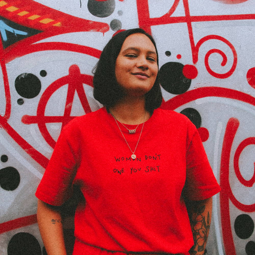 headshot of Emma in red shirt against graffiti wall