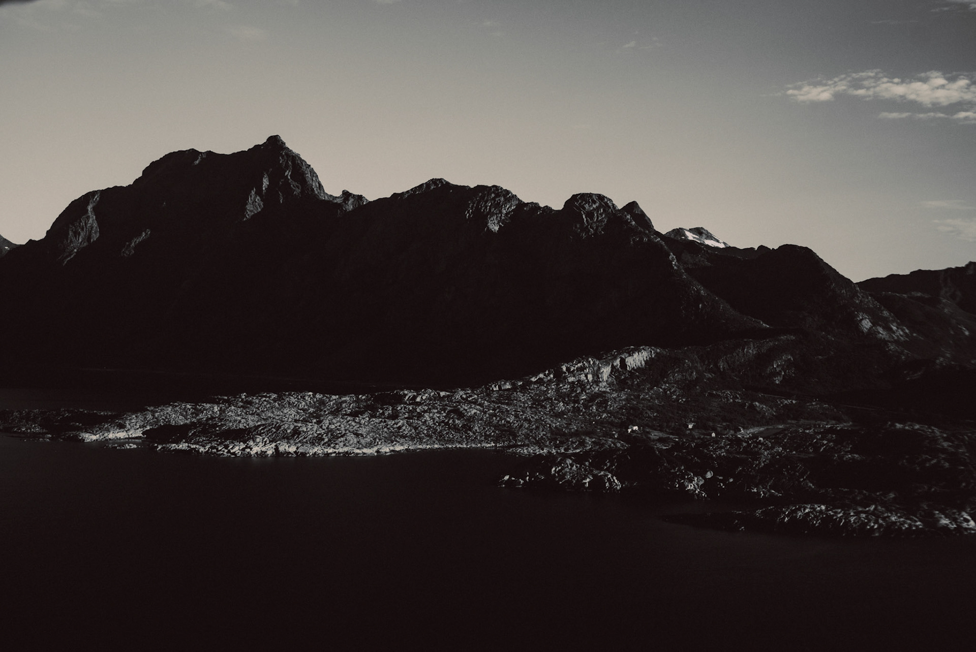 A black and white landscape photo of a rocky coast and mountains in Lofoten Islands, Norway, July 2016, Leica M.