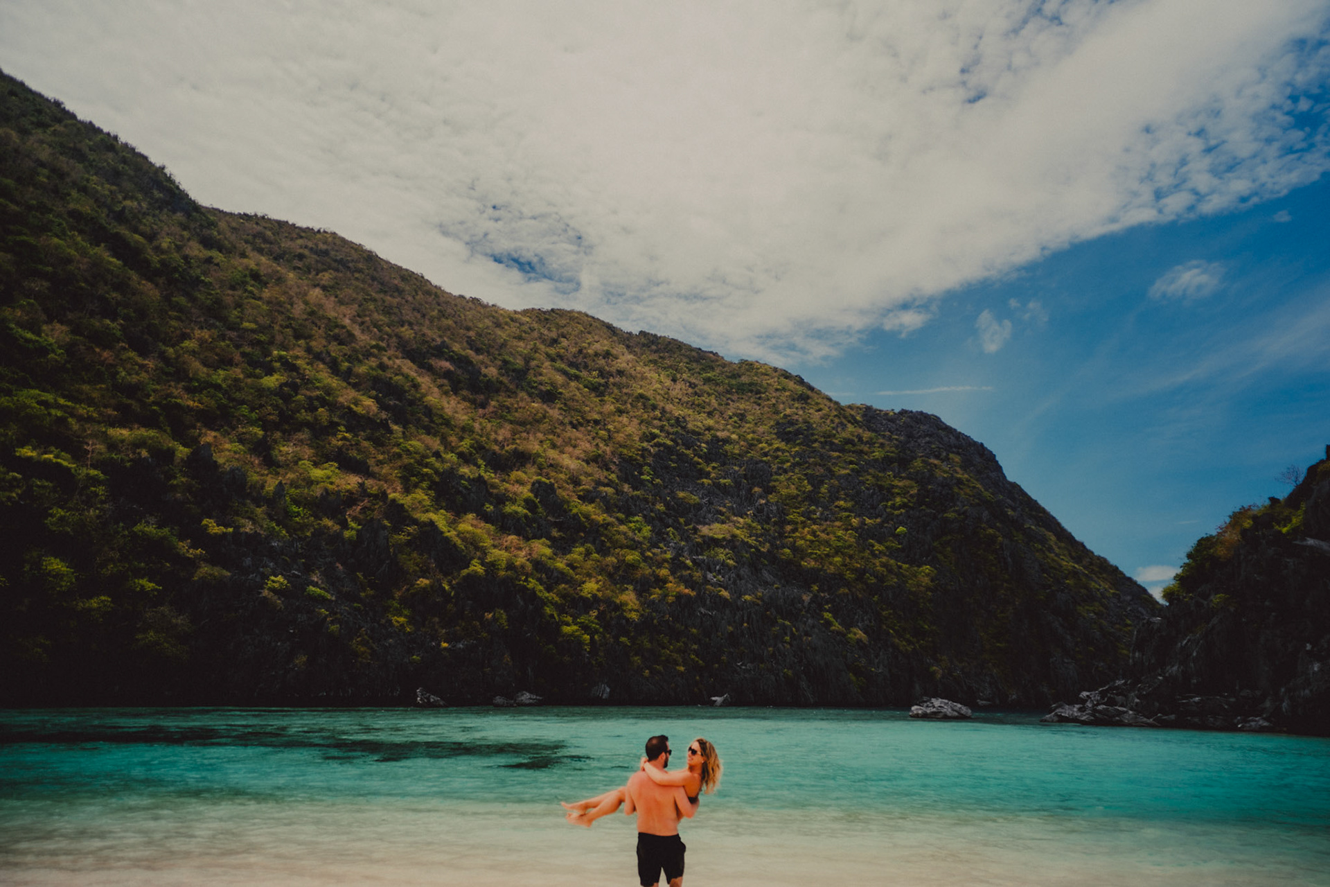 Travel and adventure couple portraits with Skipper Charters, on a cove with a hidden beach with turquoise blue water surrounded by limestone cliffs, Star Beach, Tapiutan Island, El Nido, Palawan, Philippines,Southeast Asia, March 2019, Sony A7III.