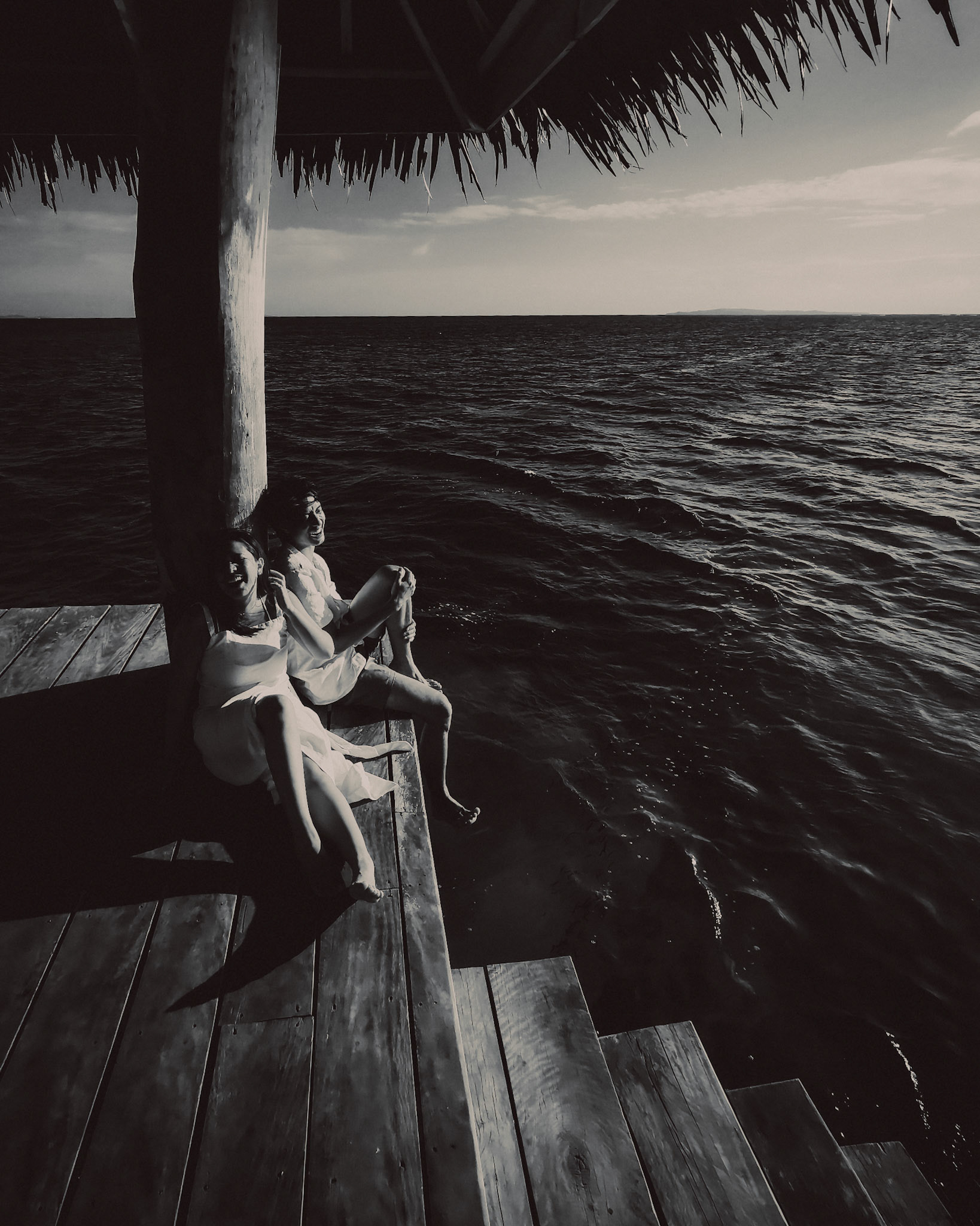 A candid black and white photo of a couple sitting on a pagoda in the middle of the sea, Nay Palad Hideaway, Siargao Island, Philippines, February 2020, Huawei P30 Pro.