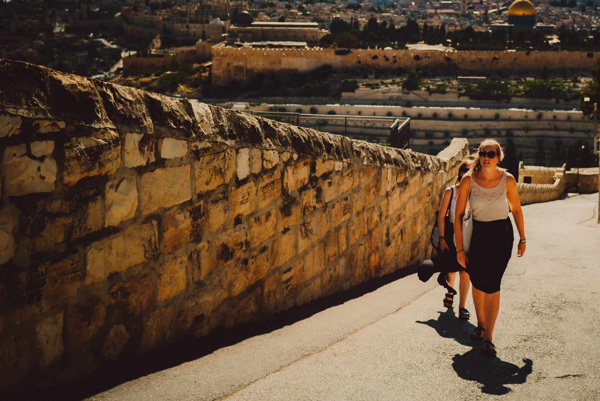 Two women walking uphill near the Jewish Cemetery with the temple mount in the background, Jerusalem, Israel, July 2015, Leica M.