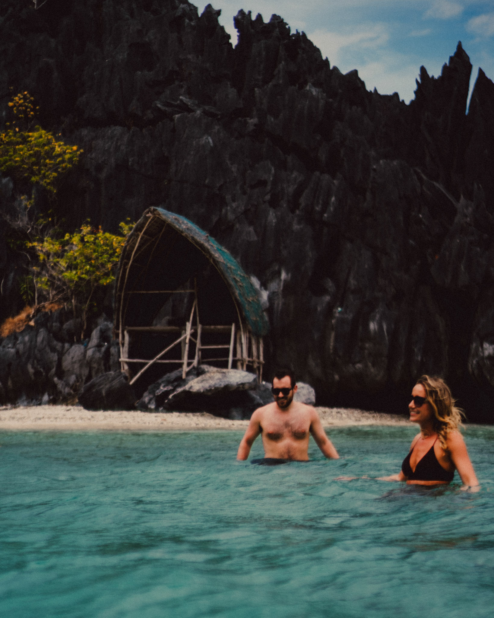 Travel and adventure couple portraits with Skipper Charters, on a cove with a hidden beach with turquoise blue water surrounded by limestone cliffs, Star Beach, Tapiutan Island, El Nido, Palawan, Philippines,Southeast Asia, March 2019, Sony A7III.