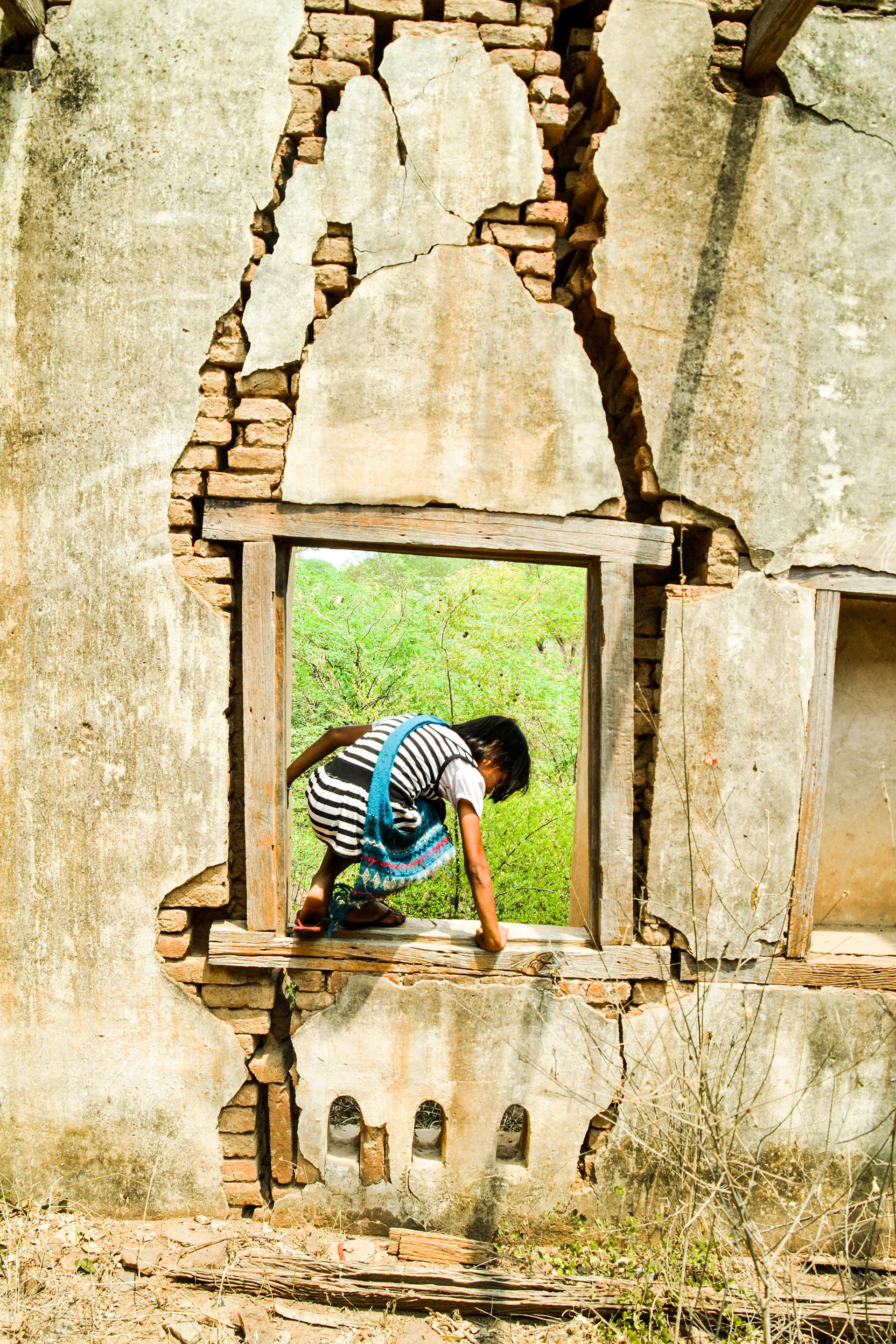 Young girl climbing through a collapsed window, Bagan, Myanmar