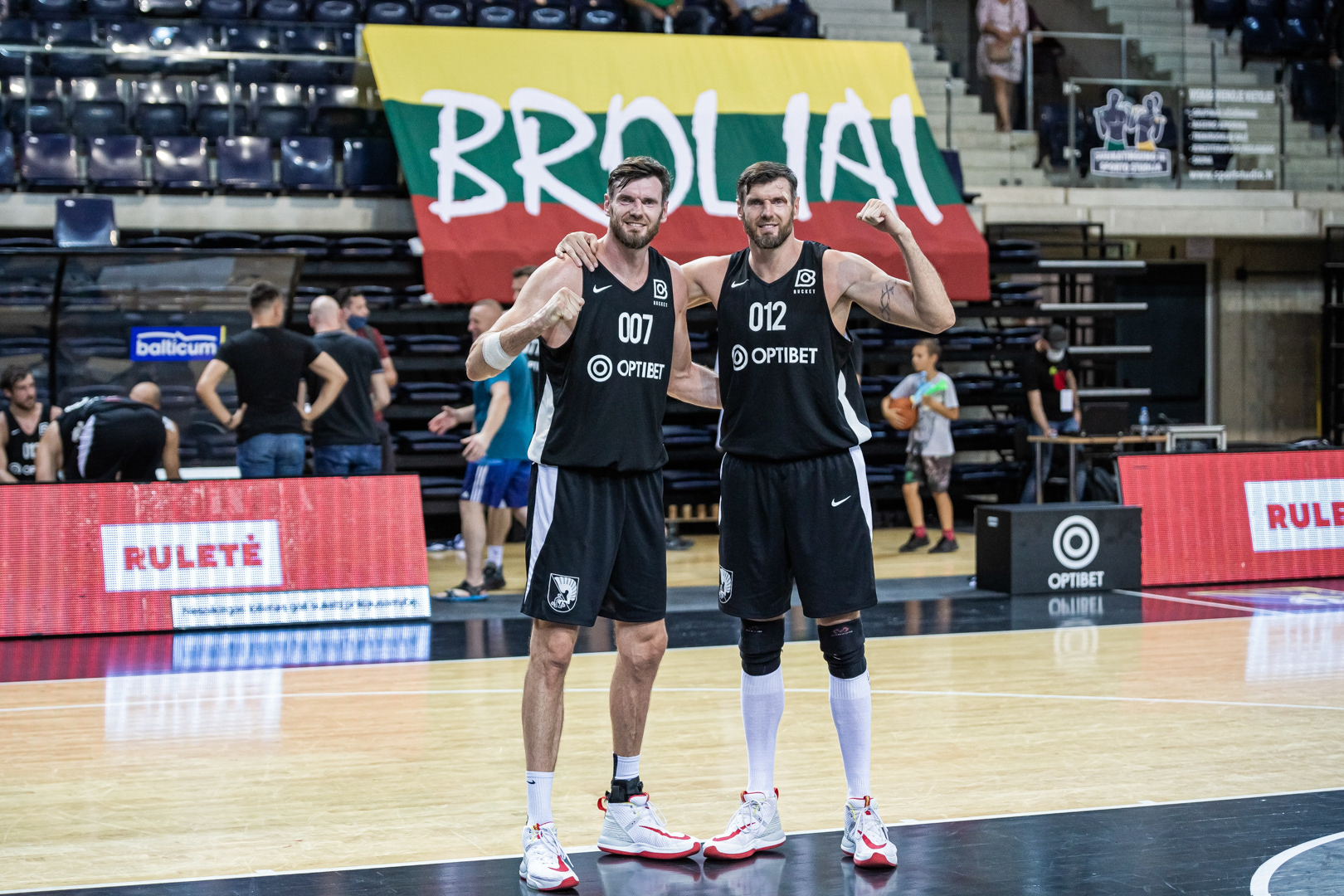 Broliai Lavrinovičiai po Bucket Summer League 2020 finalo rungtynių pozuoja sirgalių vėliavos fone