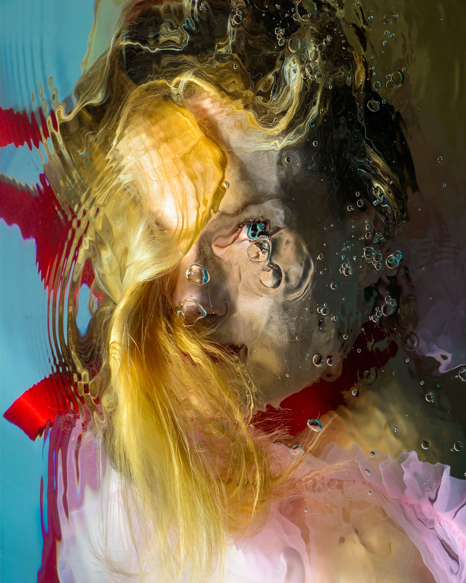 Dara is photographed while under water and lit by custom built underwater flashes. The photo is captured from above the water and has minimal post processing applied. The suspension in liquid of the model and fabrics give a soft and ethereal quality to the subject. The distortions and ripples of surface disturbance lend a painterly and expressionistic quality to the image.