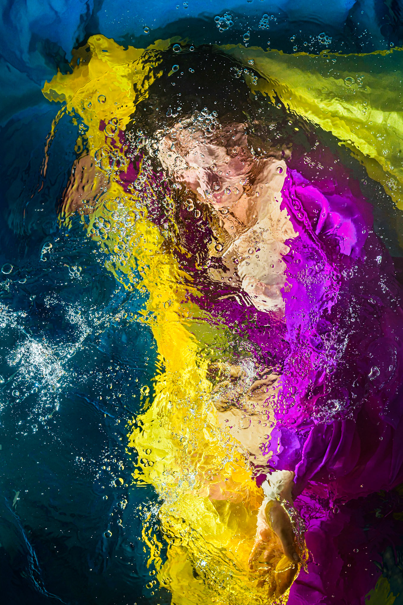 Emma is photographed while under water and lit by custom built underwater flashes. The photo is captured from above the water and has minimal post processing applied. The suspension in liquid of the model and fabrics give a soft and ethereal quality to the subject. The distortions and ripples of surface disturbance lend a painterly and abstract quality to the image.