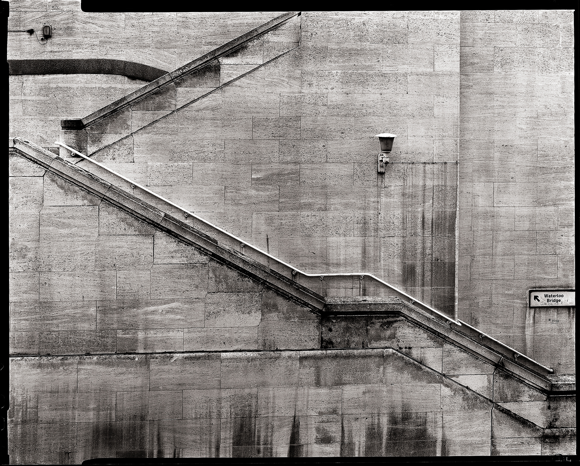 Stone wall with staircase along it. Photographed in London in black and white and with a black large format border