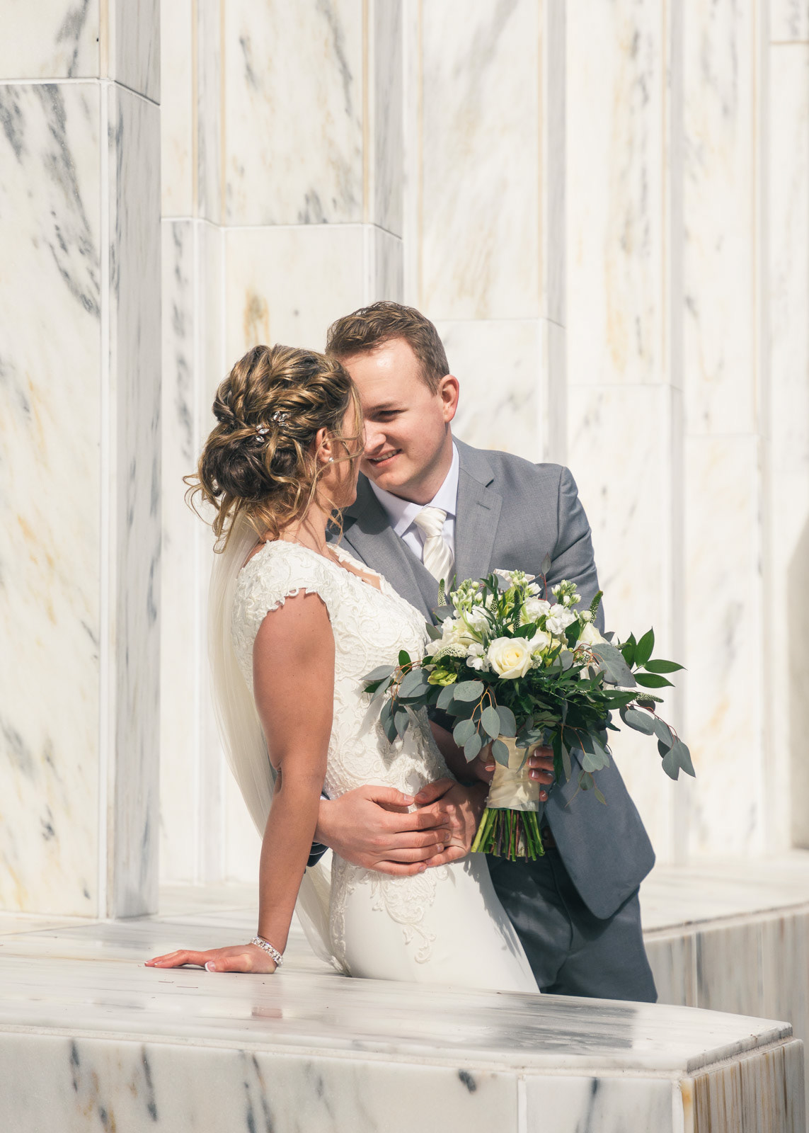 Young couple holding each other against the marble walls of Portland Oregon Temple
