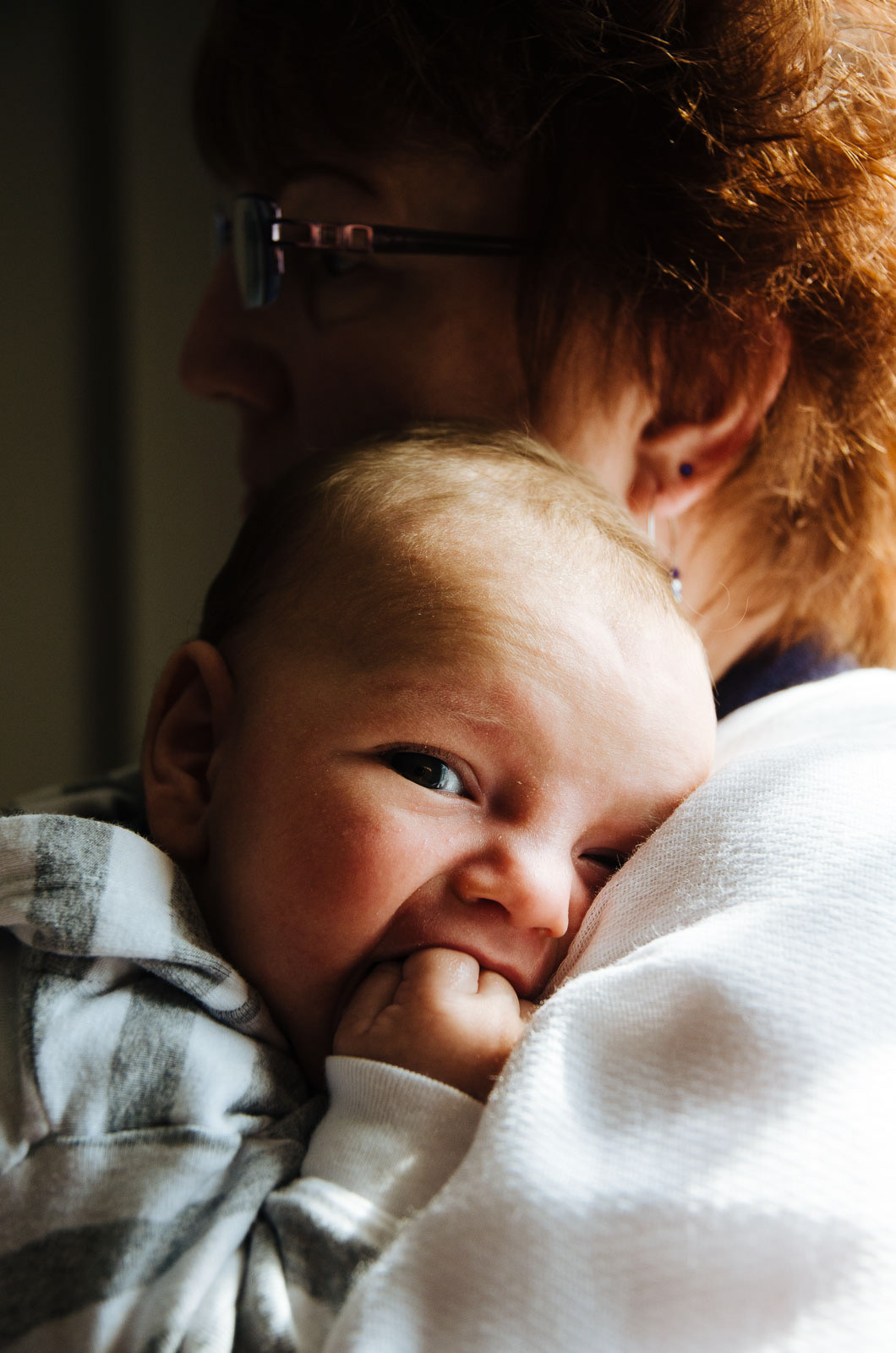 Intimate portrait of baby boy held by grandmother in soft natural light