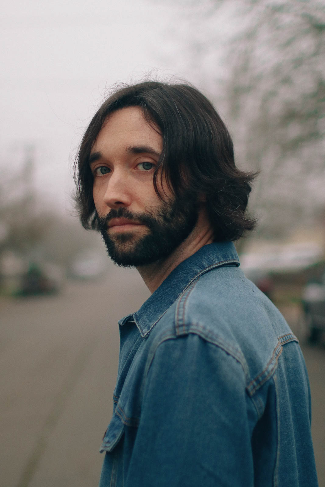 Model with blue eyes and denim jacket looks back in the gray of winter