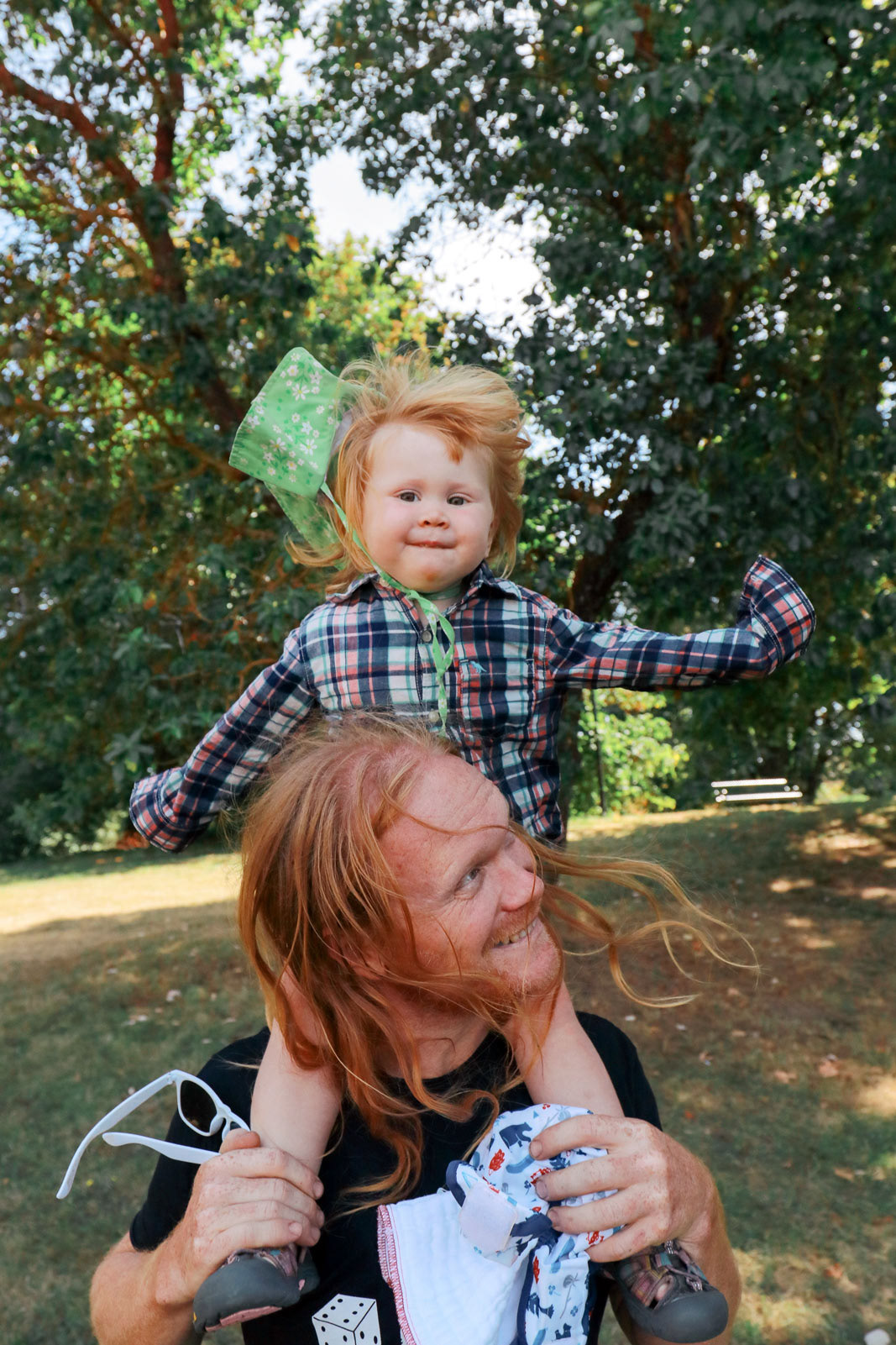 Father and son having fun outdoors in a park, riding on Dad's shoulders