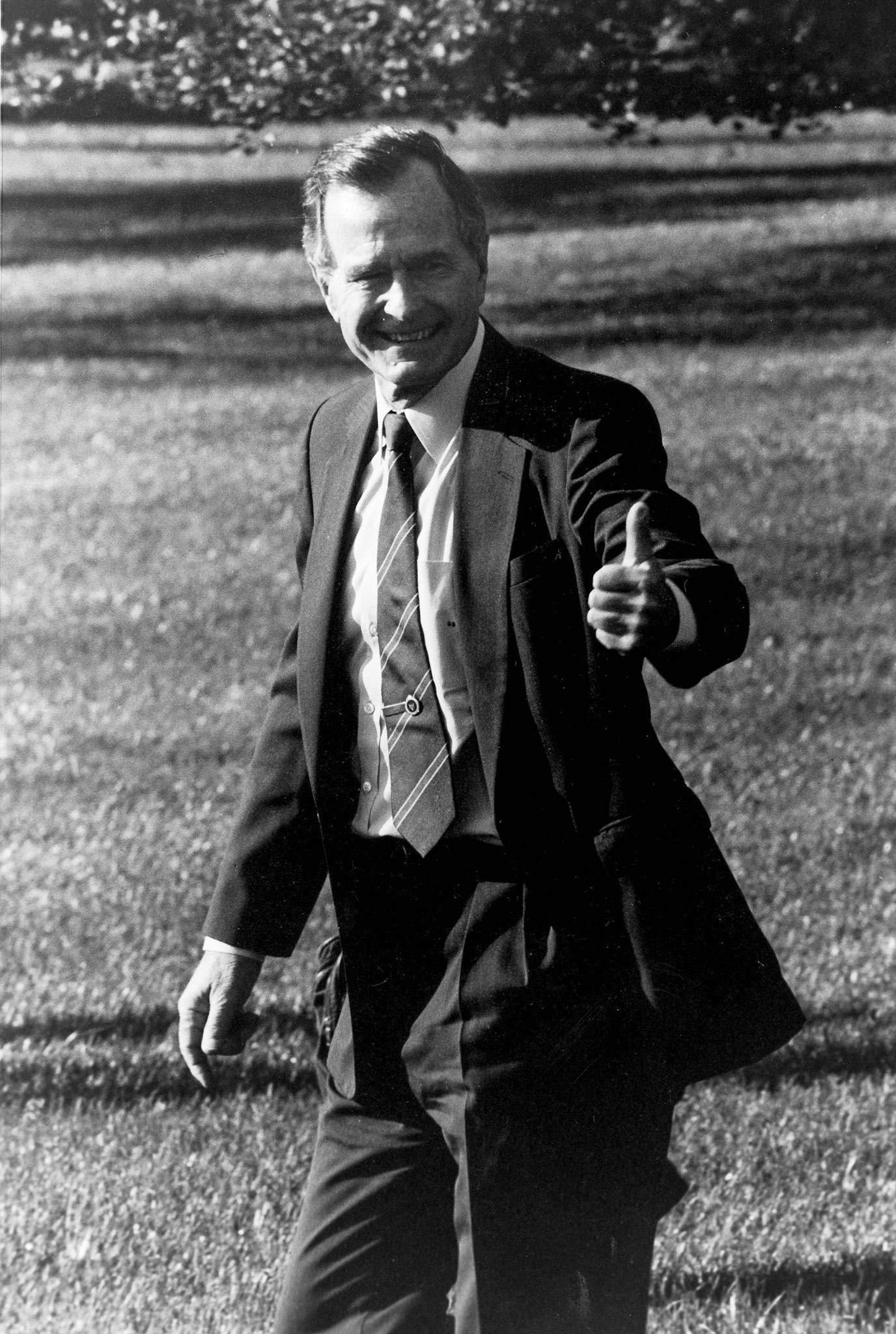 President George H.W. Bush gives thumbs up while walked across the White House South Lawn to an awaiting helicopter, October 15, 1990.