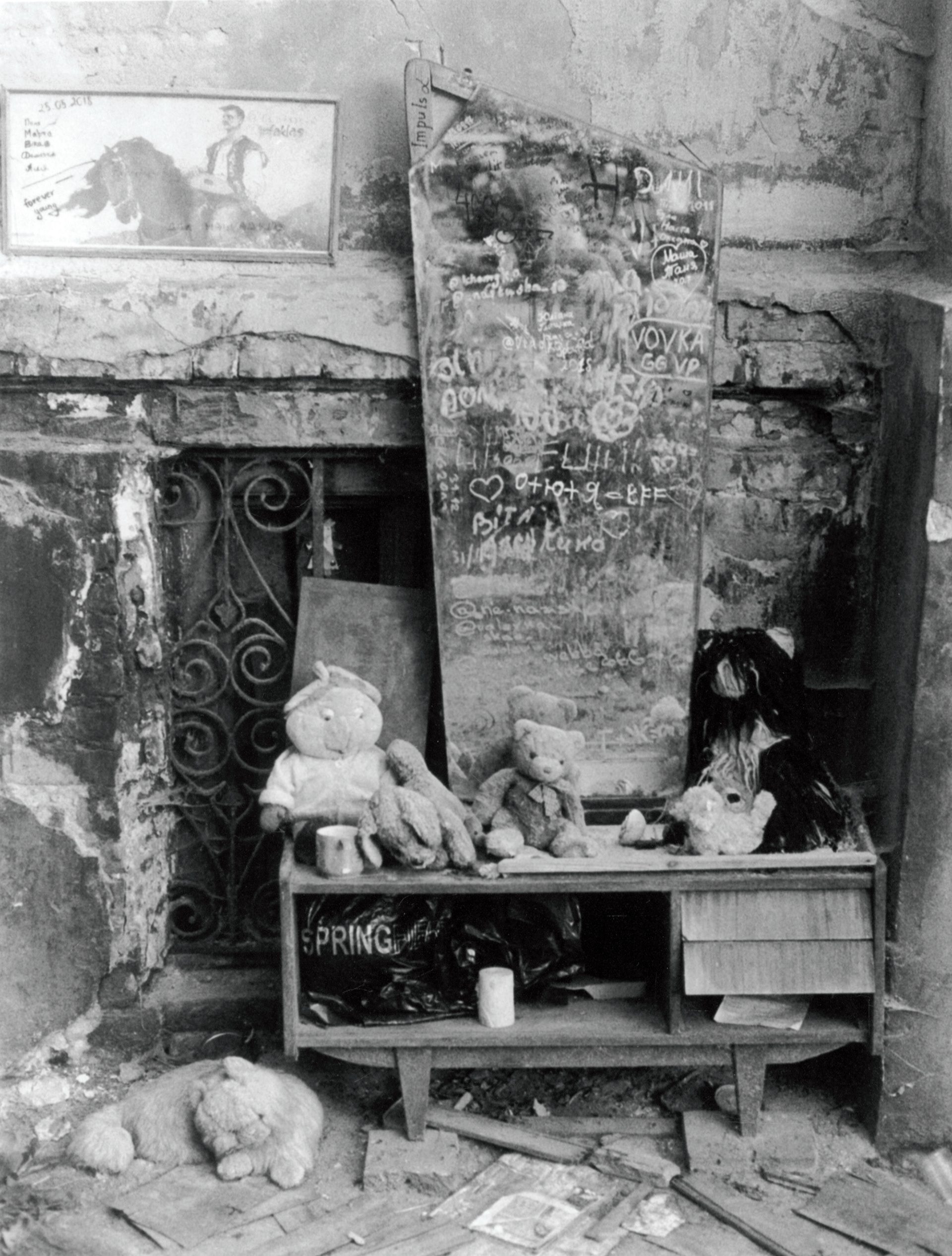 a collection of abandoned toys arrayed on a broken dressing table with mirror, the mirror is covered in scrawled notes