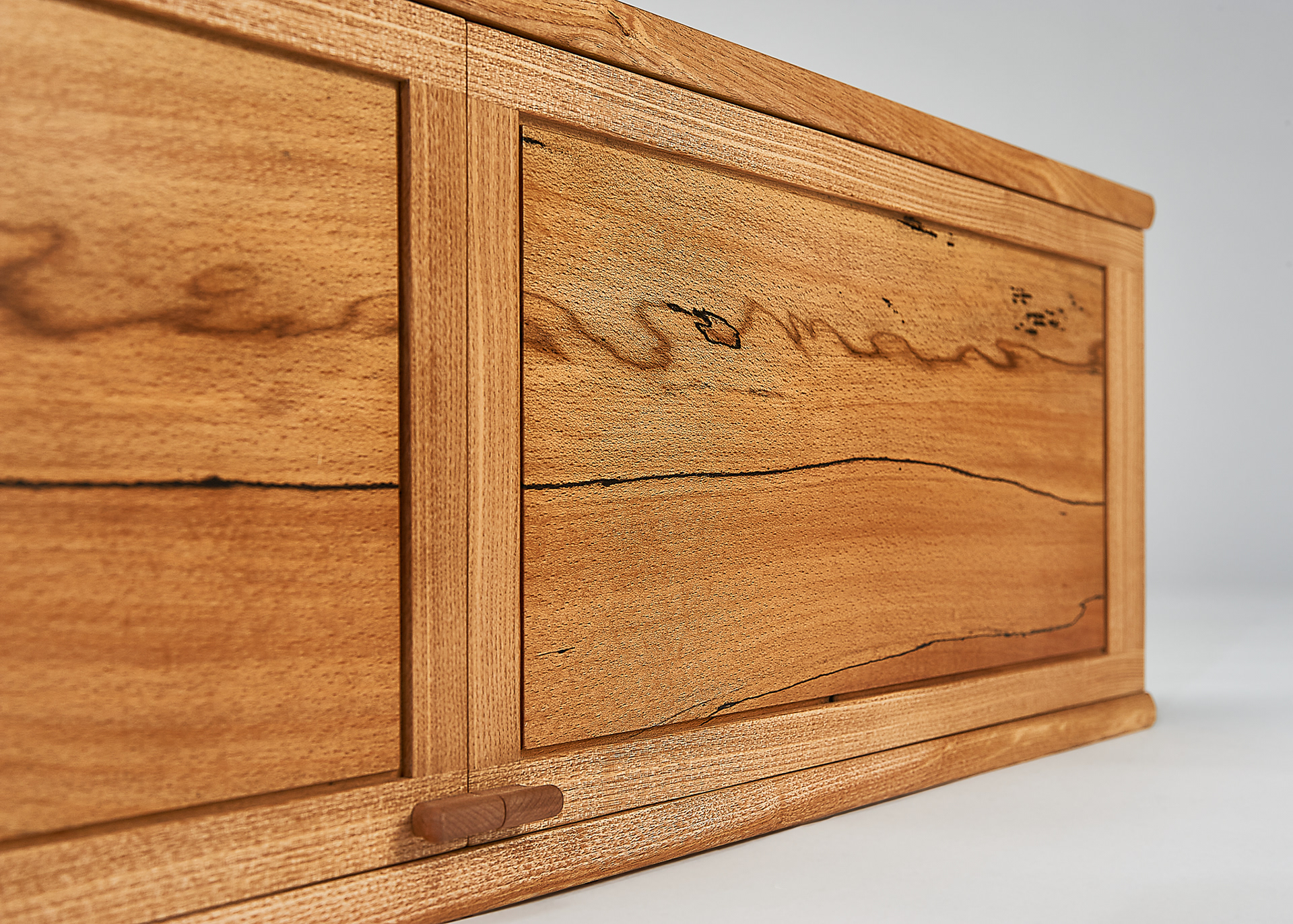 a close up of the exterior of a wall mounted cabinet, showing the detail of the spalted beech which make up the 2 door panels
