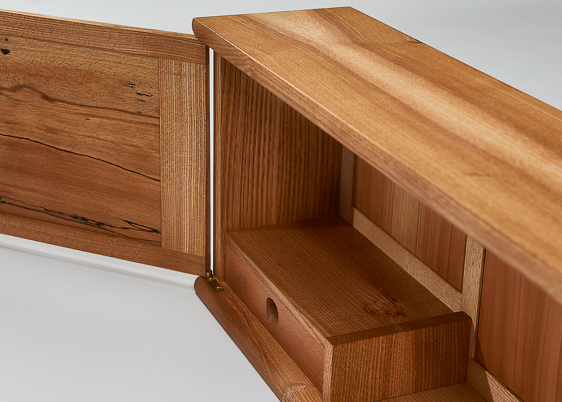the inside of a wall mounted cabinet showing the interior space, with a small drawer inside. the inside of the door is visible, showing the pattern of the wood