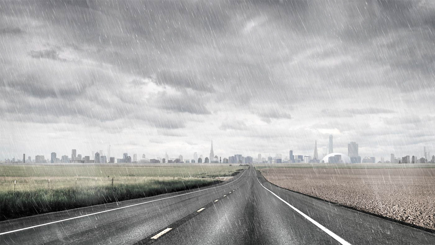 A long, deserted road stretches through farmland toward a vast city in the distance