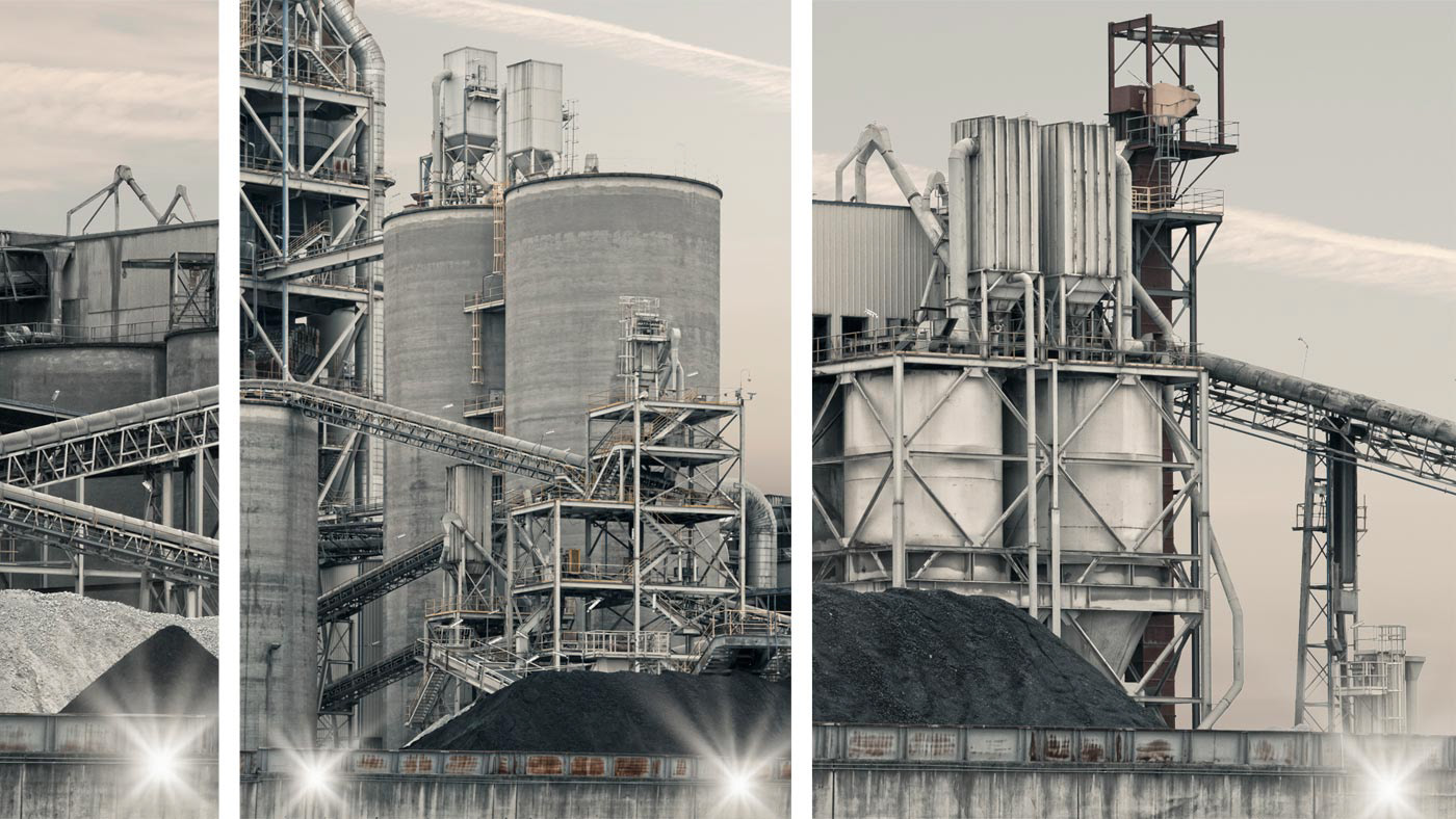 A massive cement factory radiates a soft pink glow at dusk