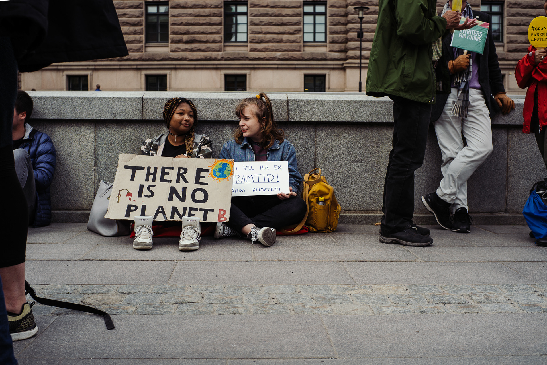 Two girls sitting on the floor with signs.