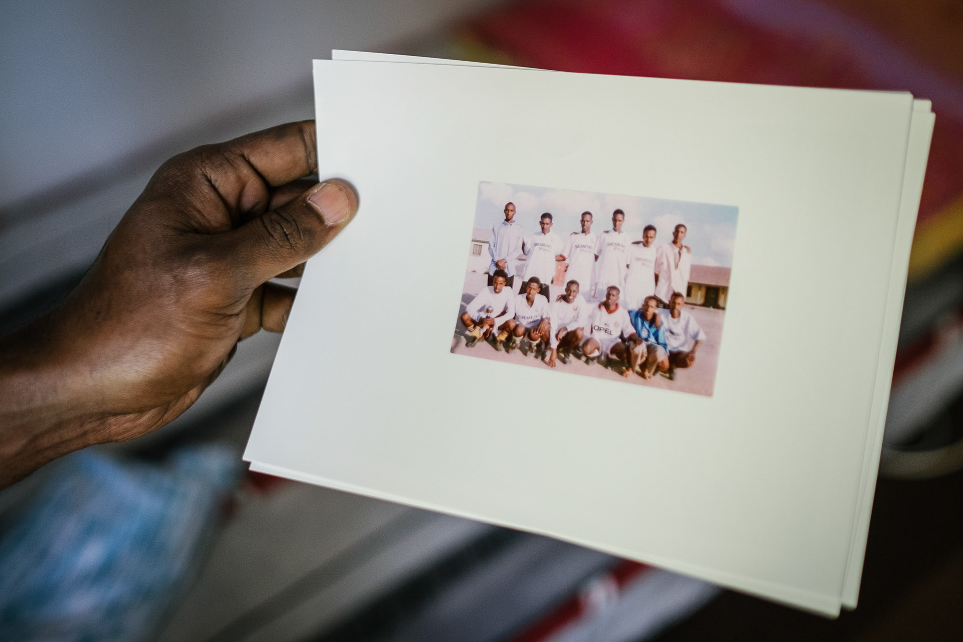 Sultan zeigt ein Foto seiner ehemaligen Fußballmannschaft aus seiner Heimat in Somalia.