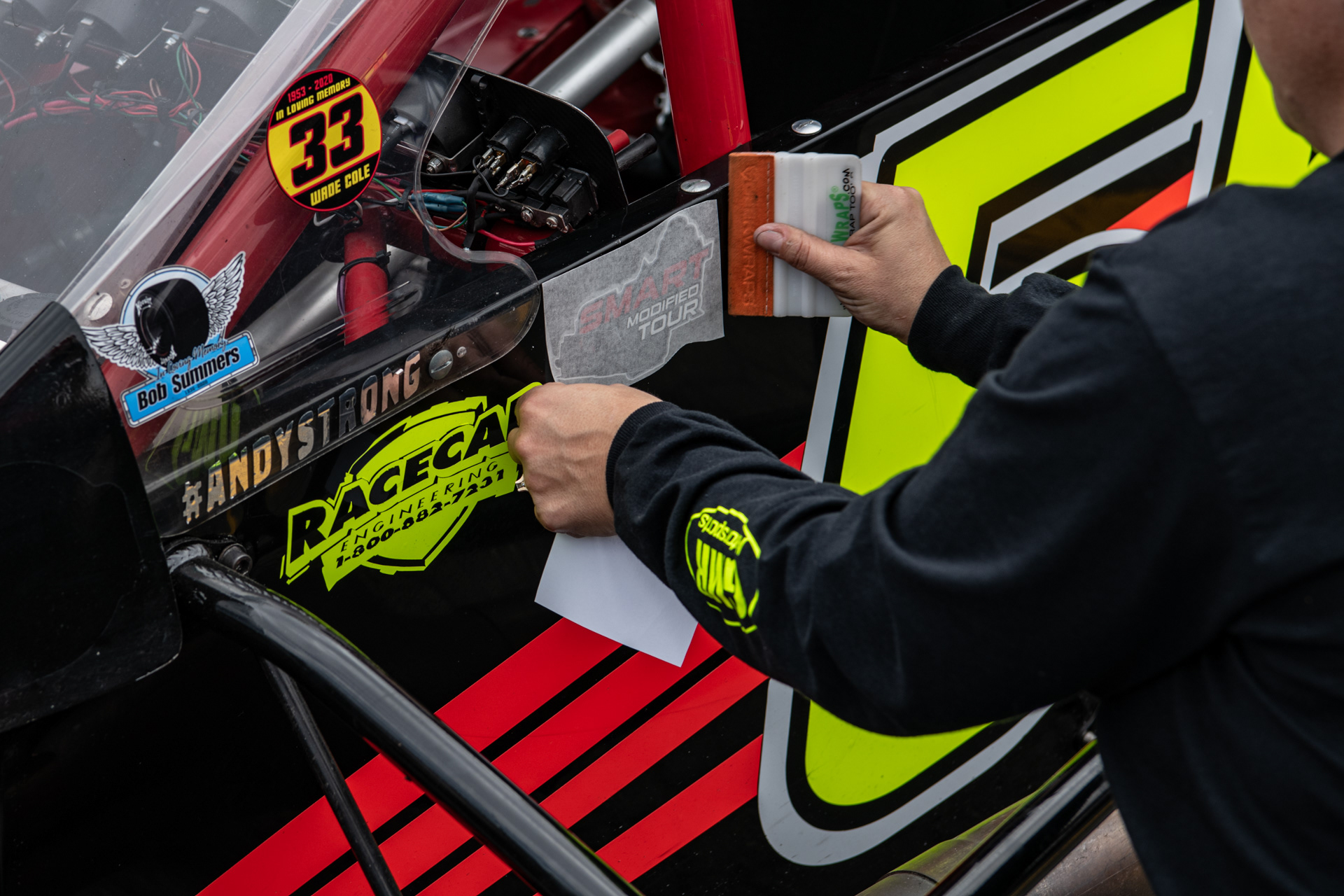 Dawn Gerstner applies new decals to the #55 SMART Tour car before practice at Caraway Speedway in Sophia, N.C. on March 13, 2021.