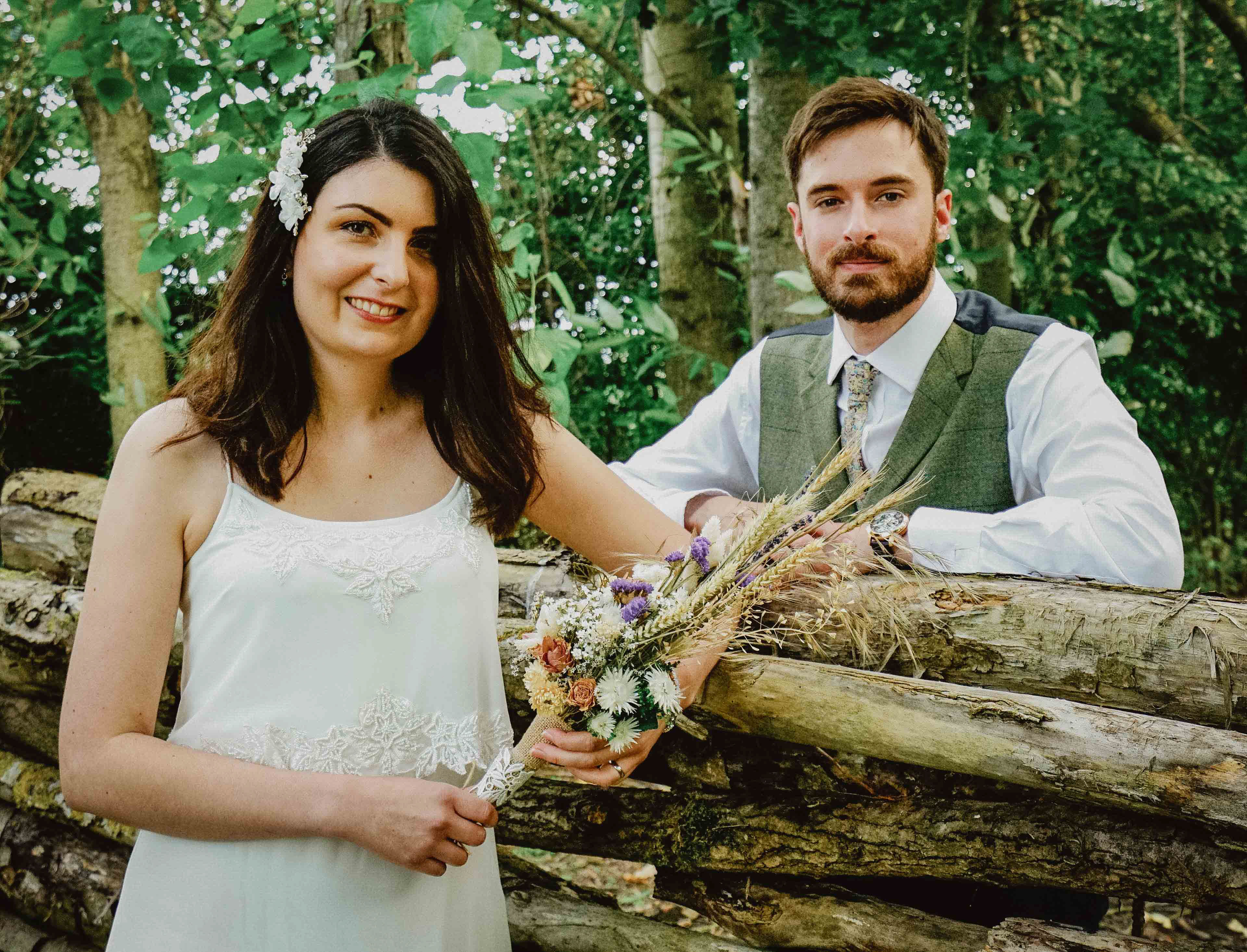 candid photo of bride and groom stood by log pile in green endeavour woodland wedding venue with david lefebvre buckinghamshire swanbourne photographer