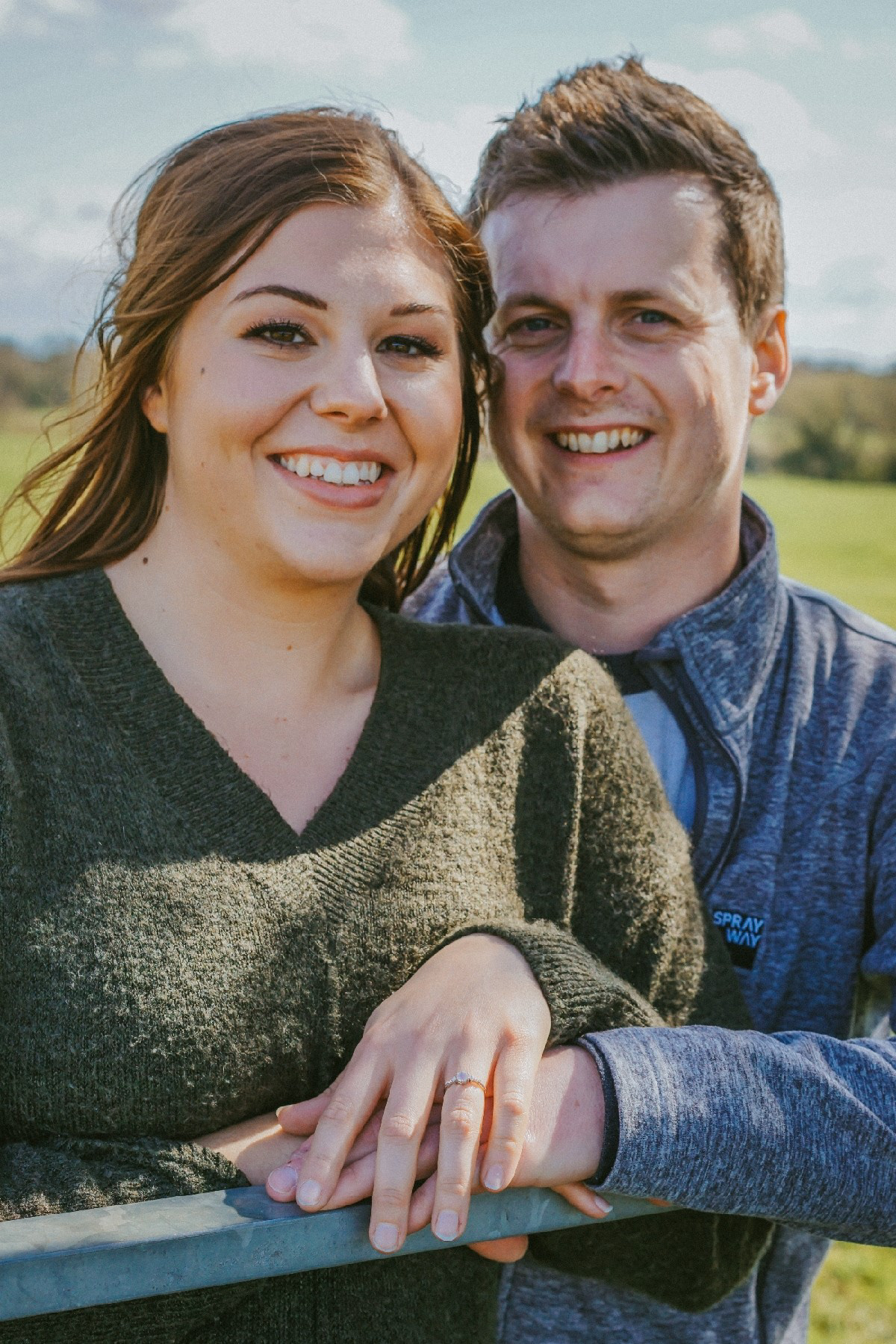 newly engaged pair stood leaning on metal gate during a pre wedding engagement shoot in spring with david lefebvre a wedding photographer based in mk and buckinghamshire in the uk