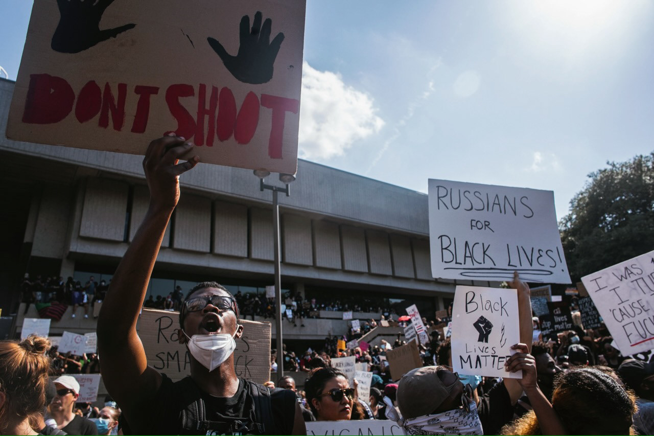 A young man holds his sign up as the crowd roars in response to another protestor shouting from a megaphone.