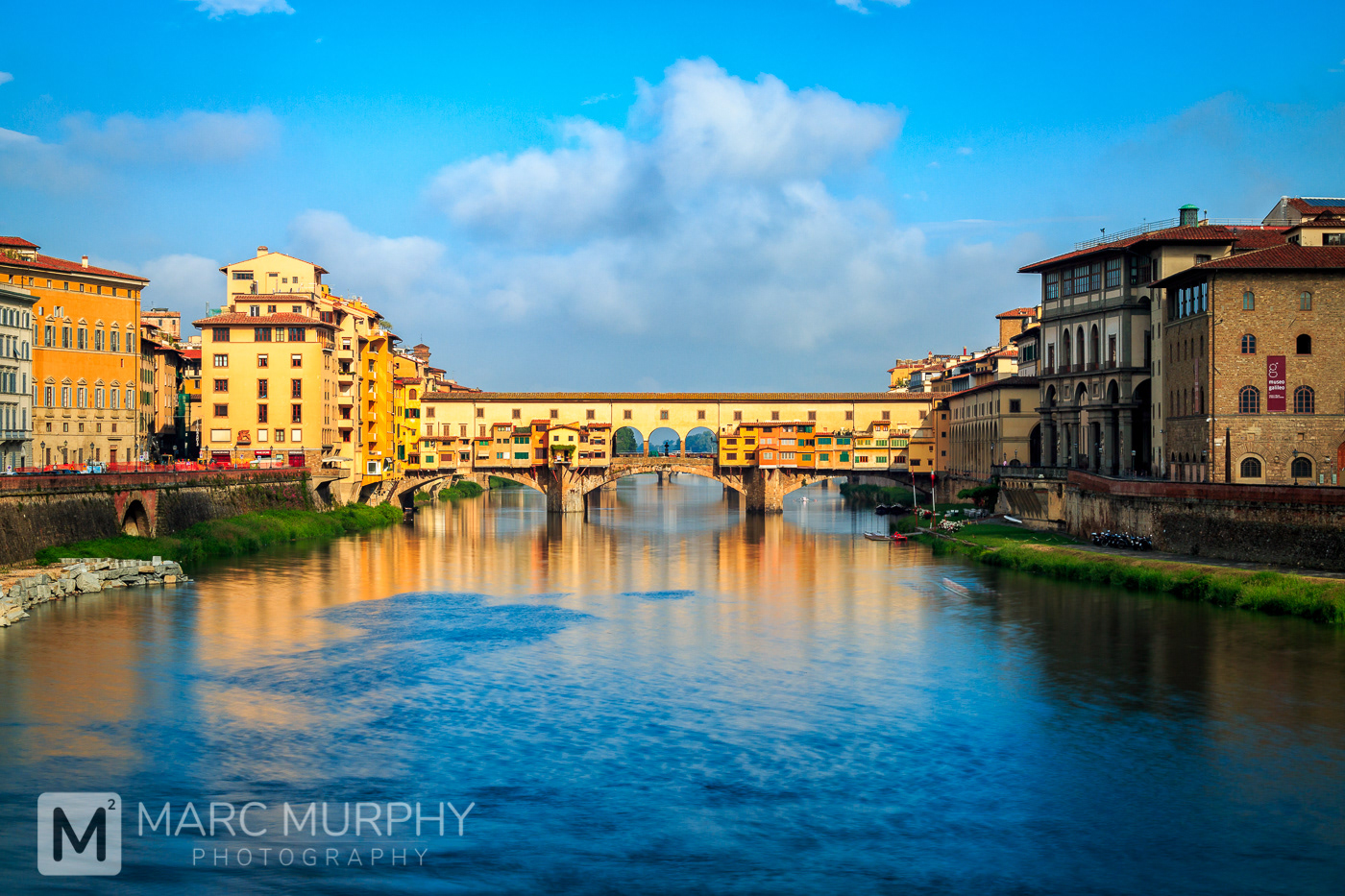 Florence Italy Ponte Vecchio Bridge at Sunrise with Arno River in Foreground, Clouds and Blue Sky