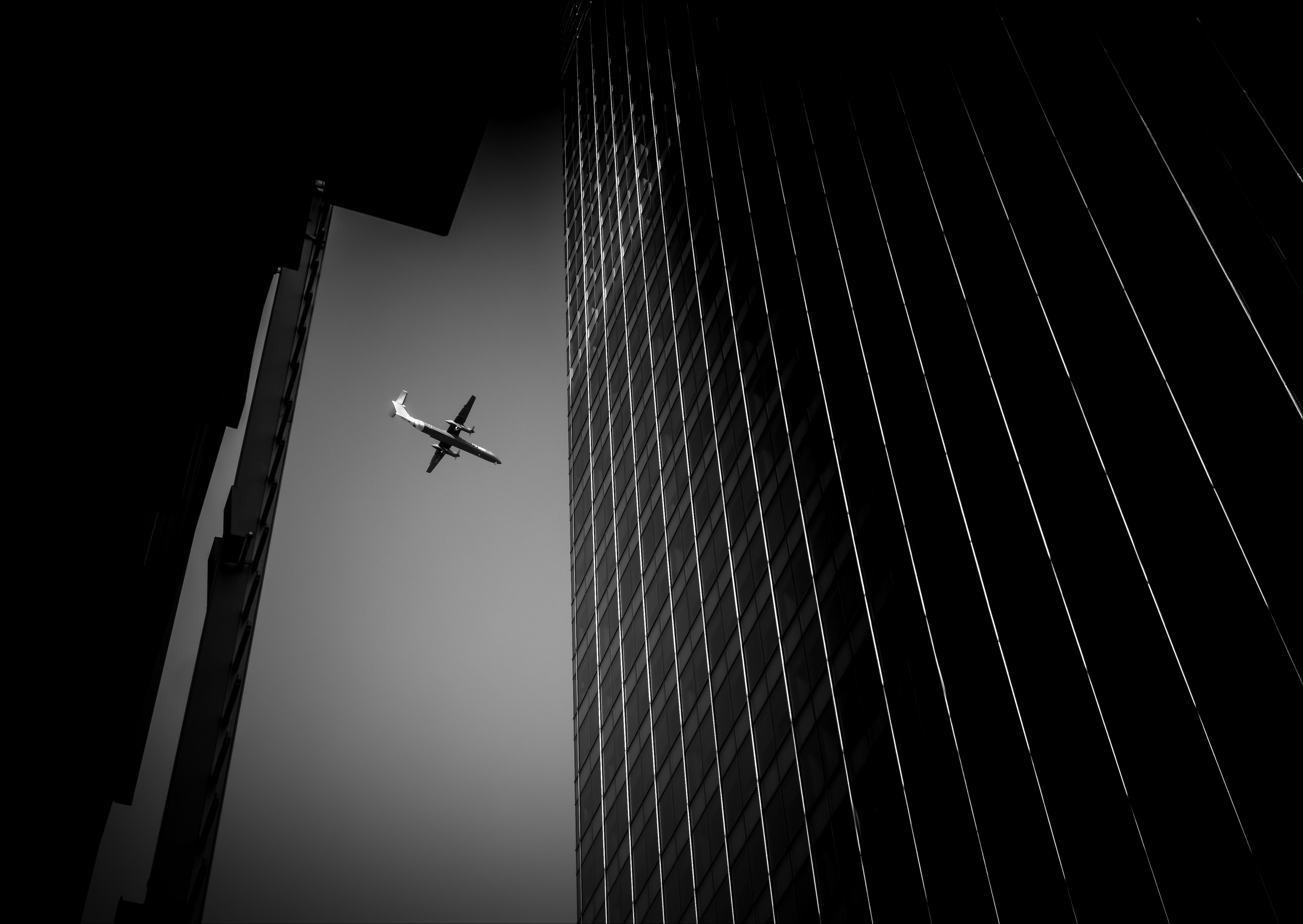 plane flying between two buildings. black and white photograph