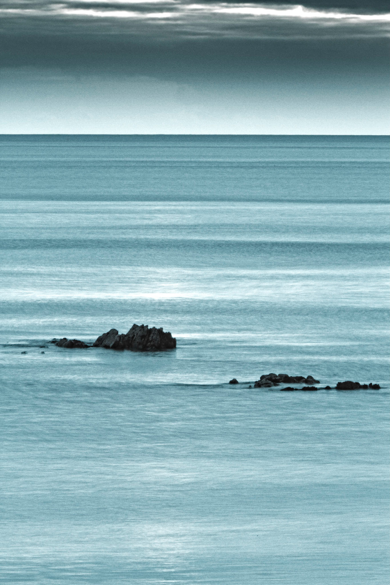 Rocks protrude through a light blue ethereal sea.