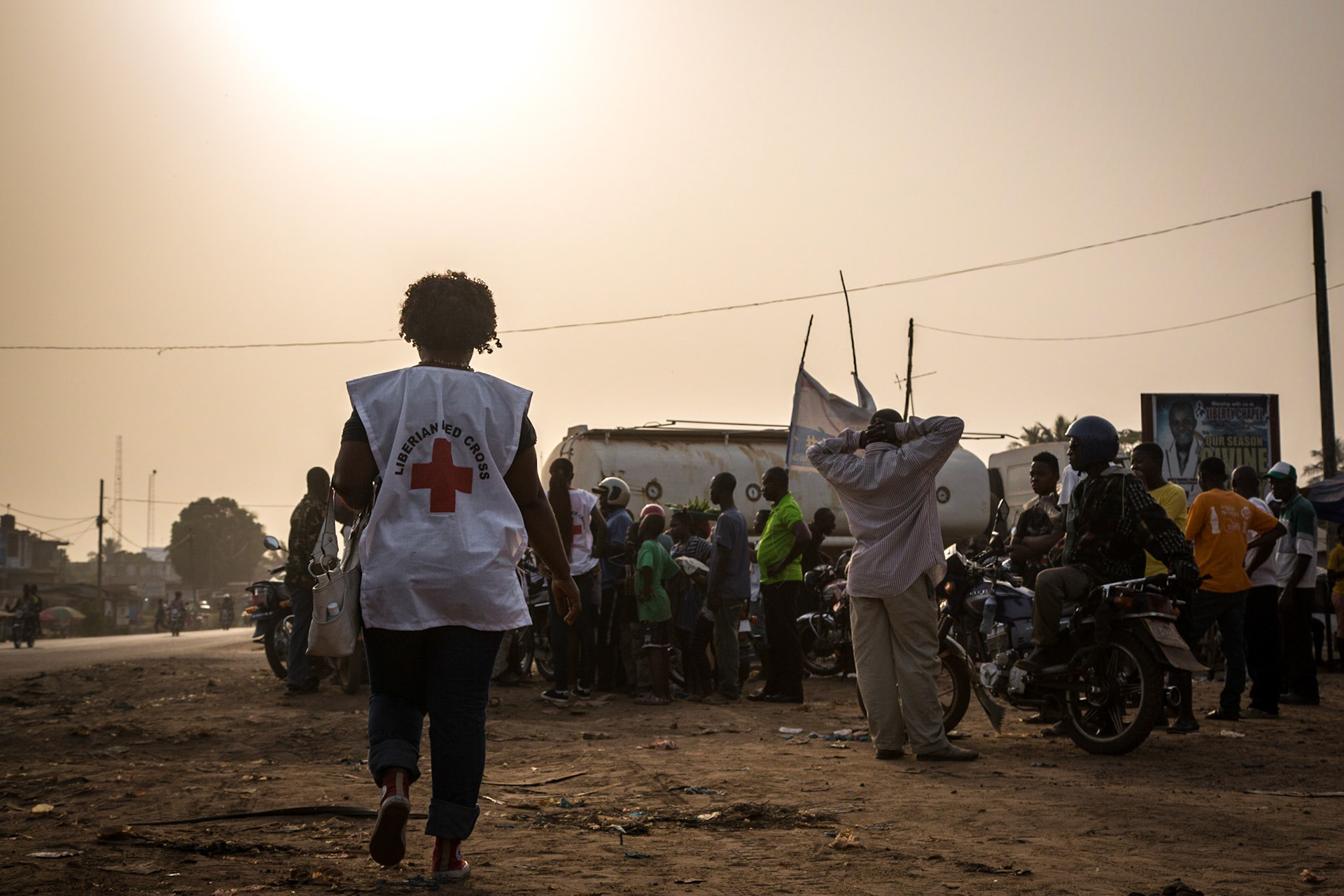 Liberia; Montserrado, 16 December 2014. Liberian Red Cross volunteers engage with market-goers. These volunteers explain the need to continue Ebola prevention activities, especially during the holiday season.   Volunteers of Liberia National Red Cross Society are carrying out focused community engagement and social mobilization in the lead up to Christmas, to help prevent the transmission of Ebola.   Photo: Stephen Ryan / IFRC
