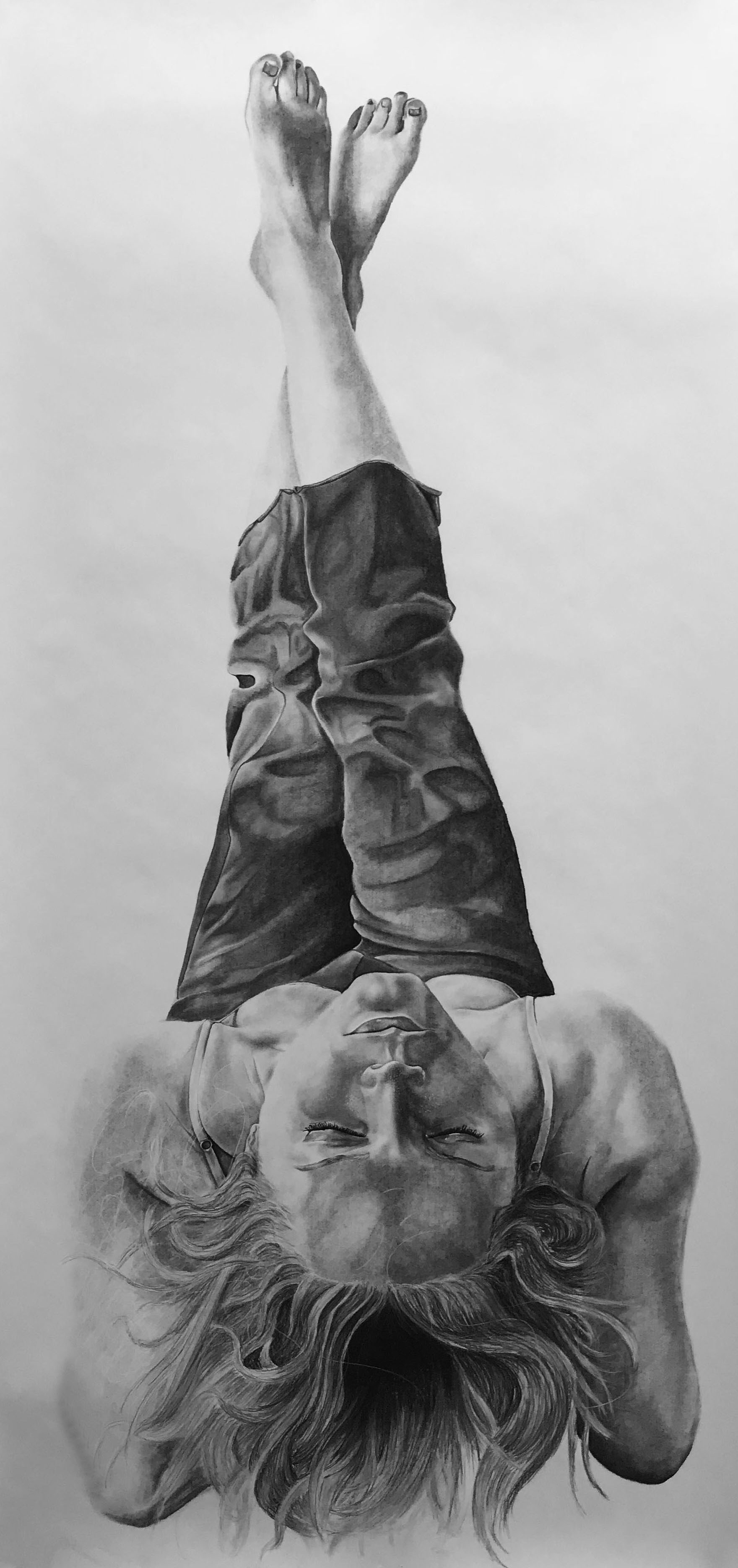 Large scale charcoal drawing of Abbey Miller on her backside with legs stretched straight up, head is tilted back.