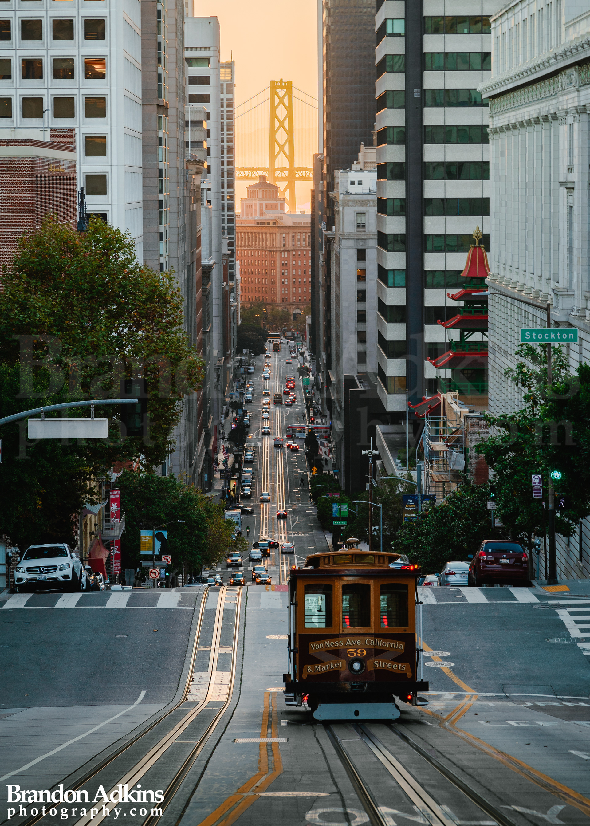 Fine art photography of trolley heading down hill on California Street with Oakland Bay Bridge in the background in San Francisco, California