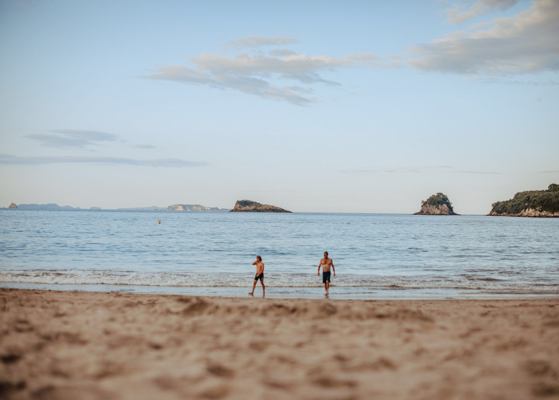 Father and son emerging from the ocean at Hahei at dusk