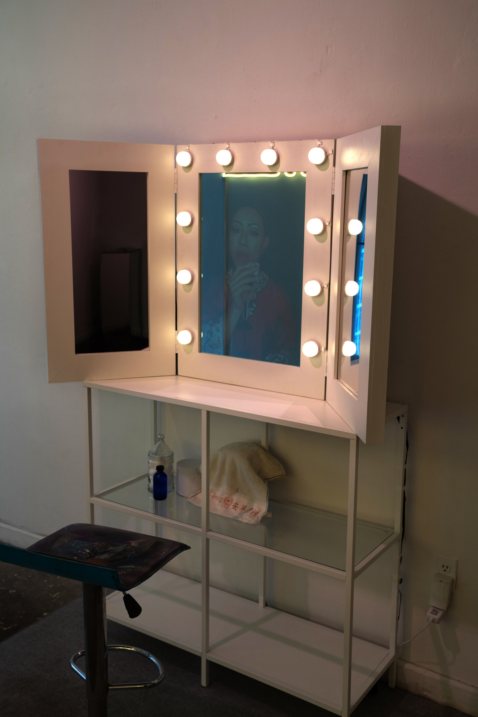 A reflection in a vanity mirror of a person taking off makeup