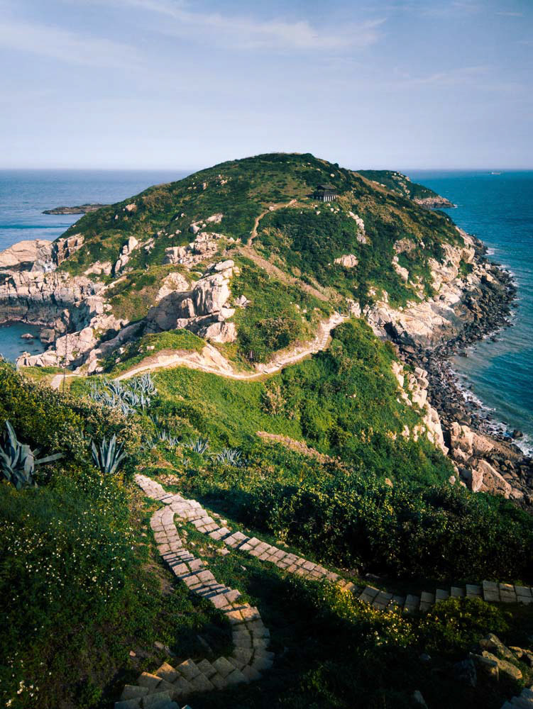 北竿鄉螺蚌山步道,在下午夕陽時分時,日落位於畫面右側,映照出海面山脈的翠綠與沈穩