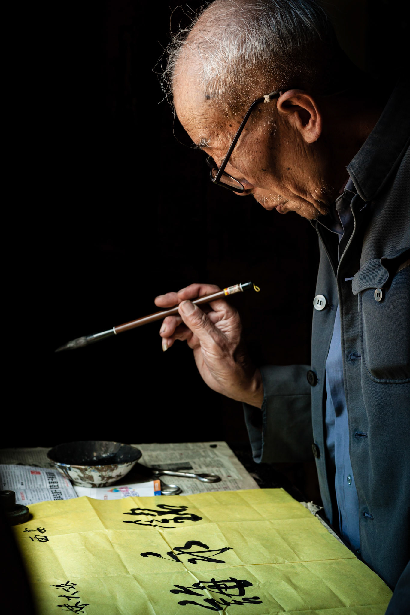 A Chinese Calligrapher making signs using traditional calligraphy in his shop in Shaxi, Yunnan Province, China.