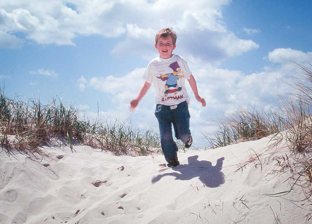 young child playing in the sand dunes of Cape Cod on a sunny day