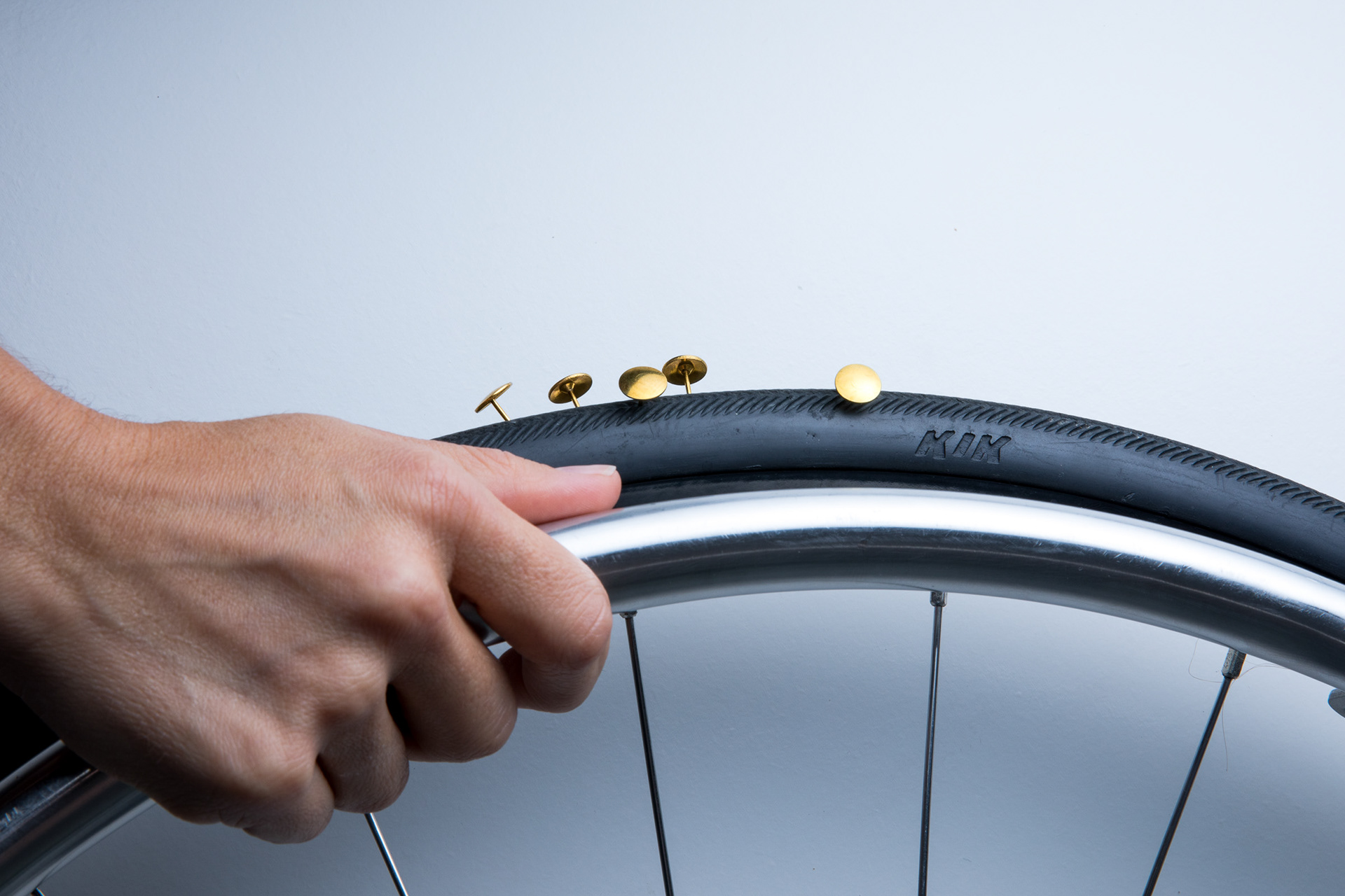 Evi's hand grasping her wheelchair tire with thumbtacks stuck in the wheel