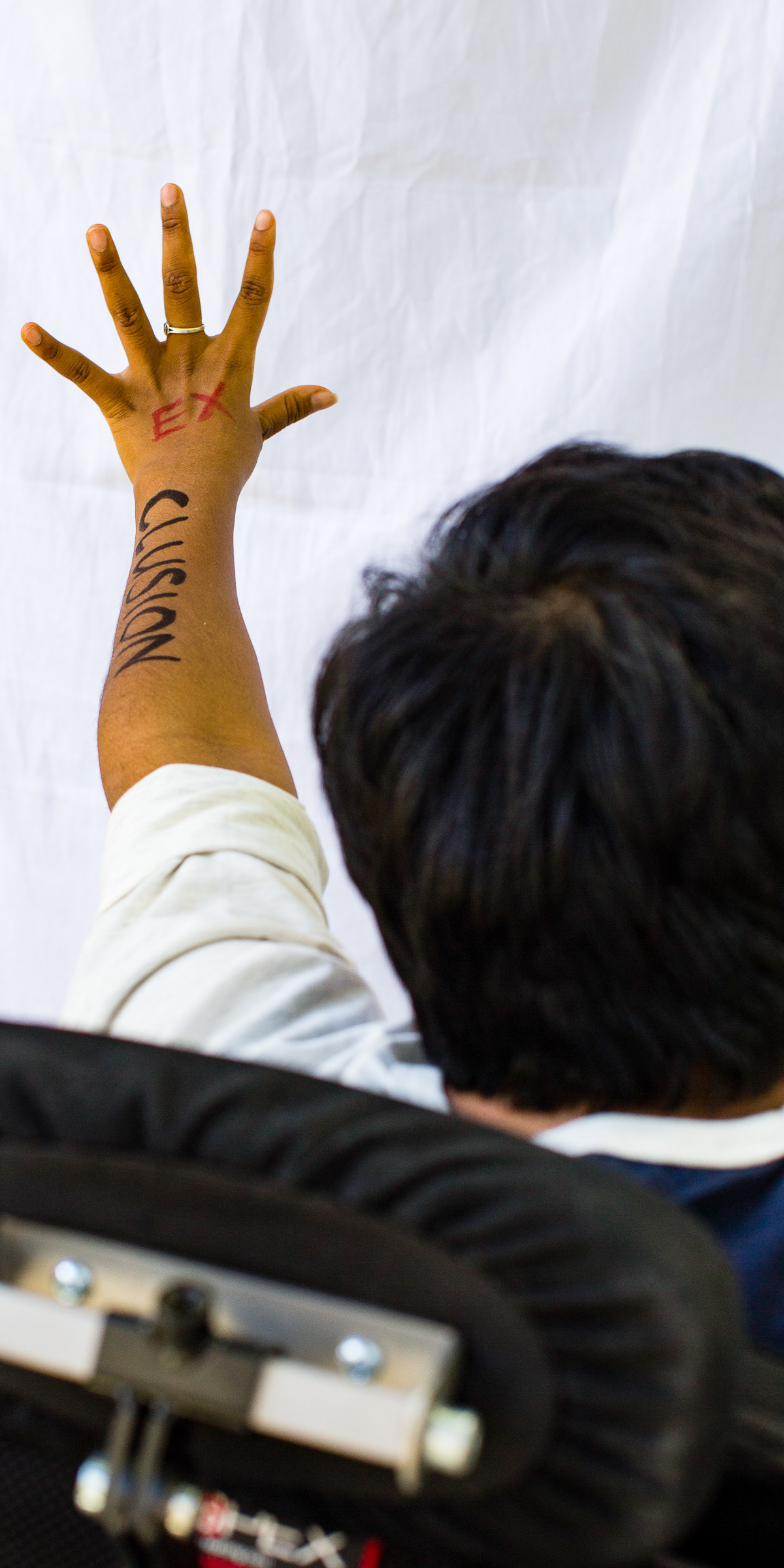 Marusha's arm extended with the letters EX and CLUSION written on the arm