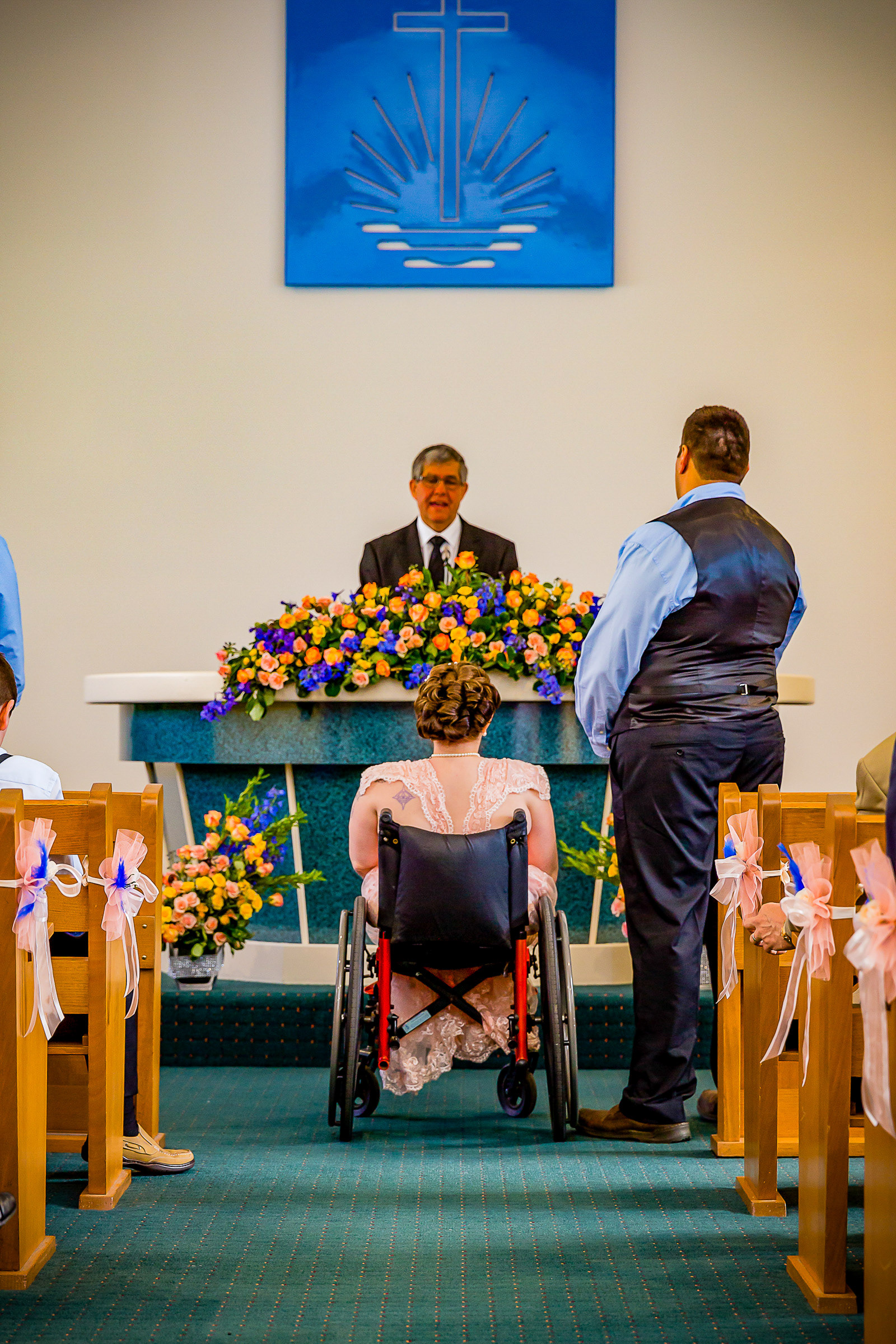Malissa in her wheelchair and her groom on her wedding day, facing the altar