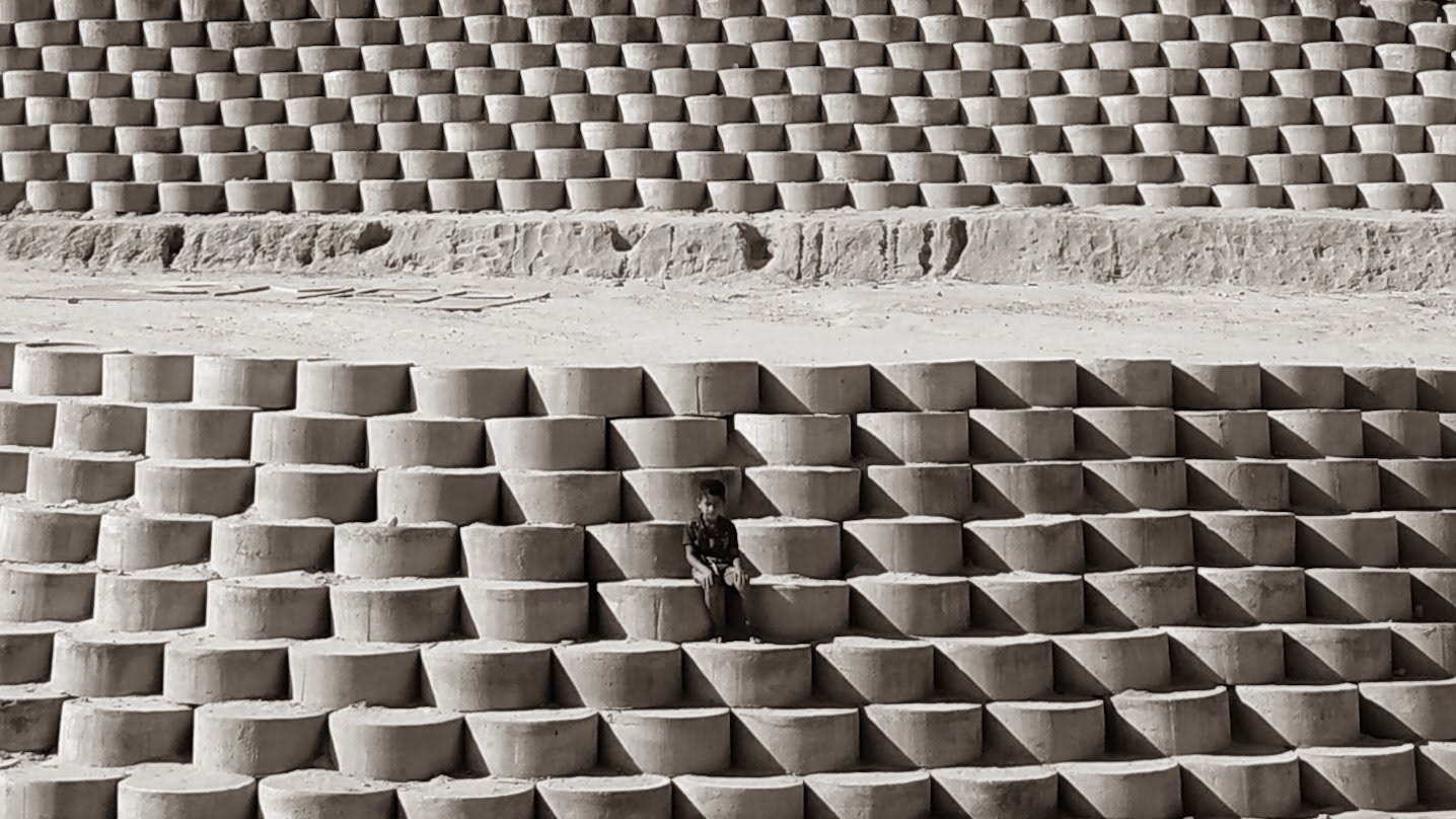 Mehrooz - A boy sitting on symmetrically arranged concrete rings designed to prevent landslides during the monsoon season