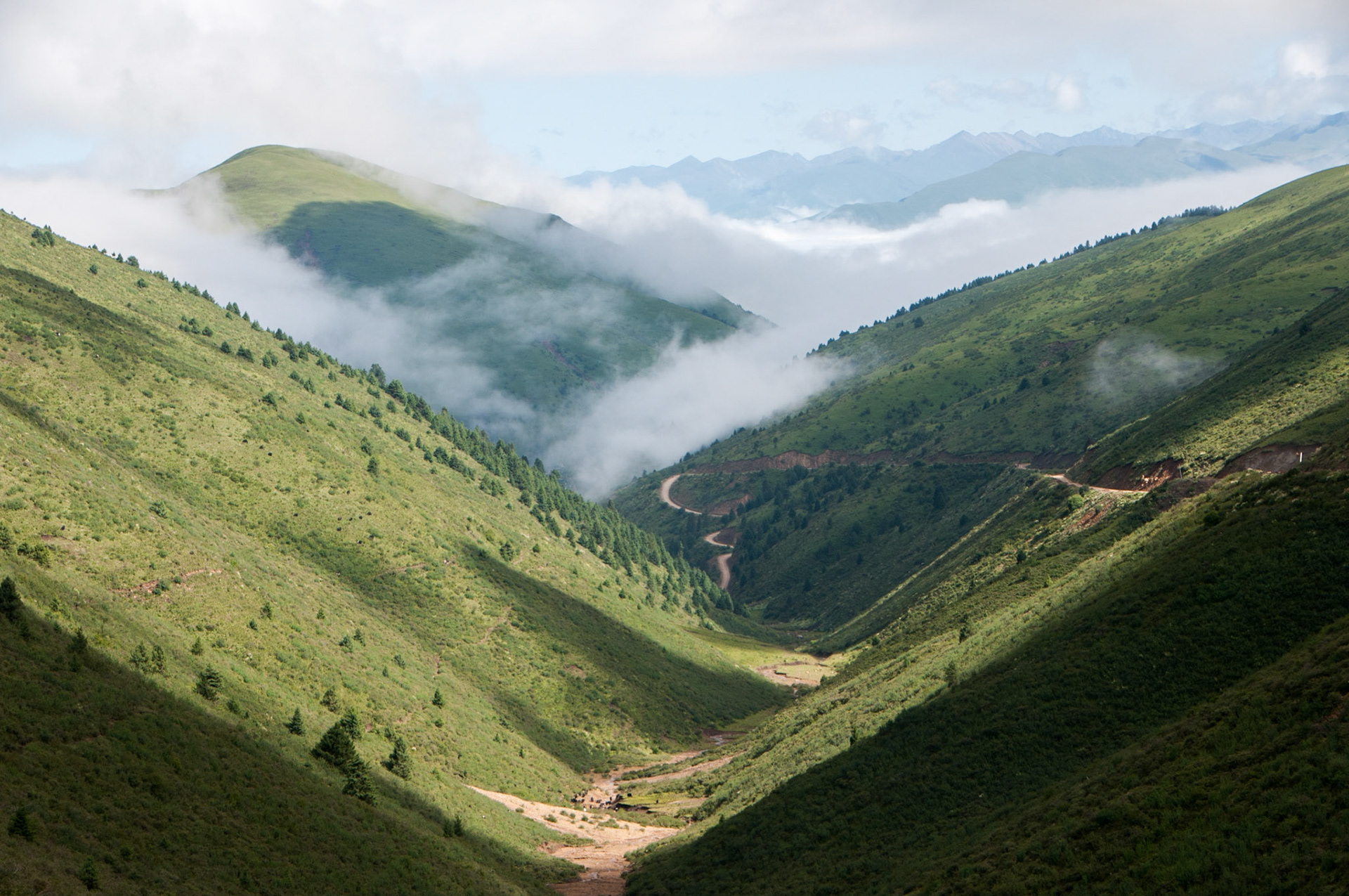 China, Eastern Tibet or Western Sichuan, also known as Kham, a road winds through a grass covered valley.