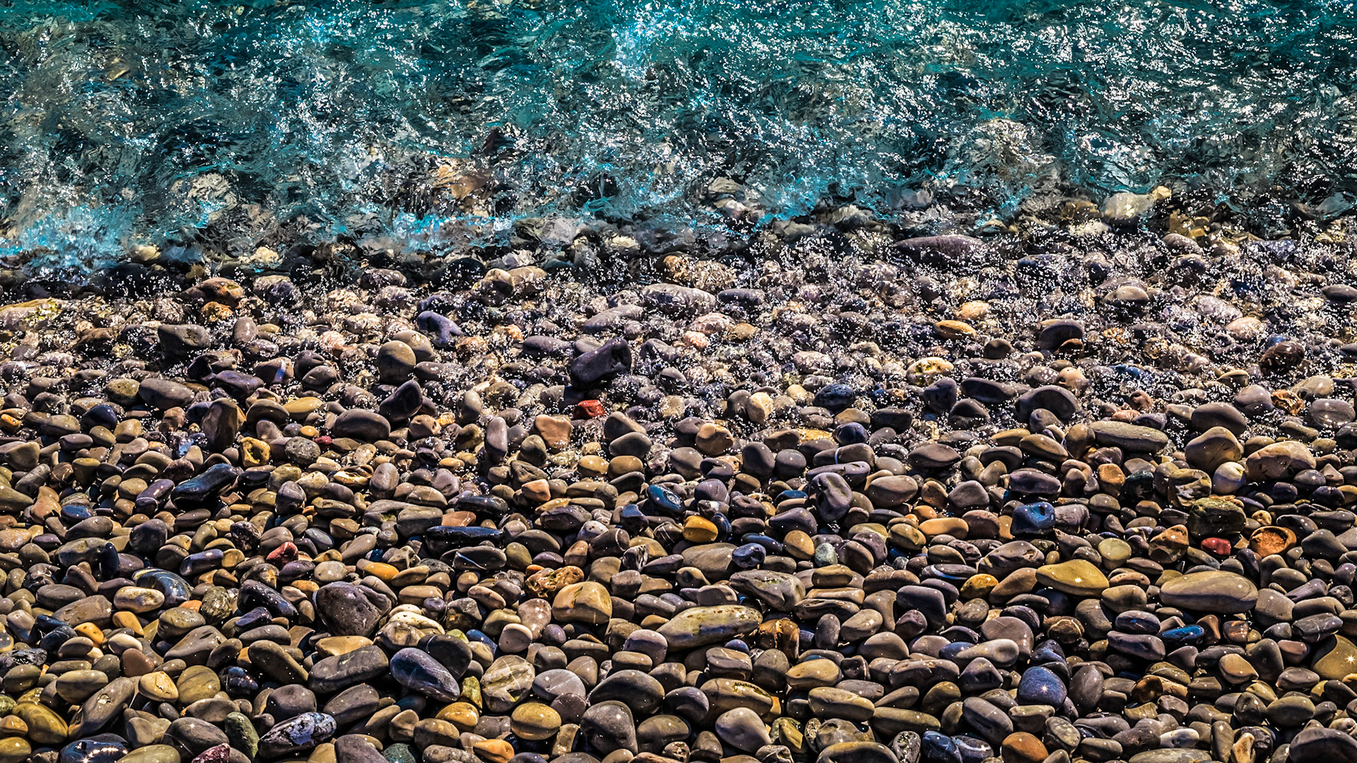 Tides wash a pebble beach during the day.