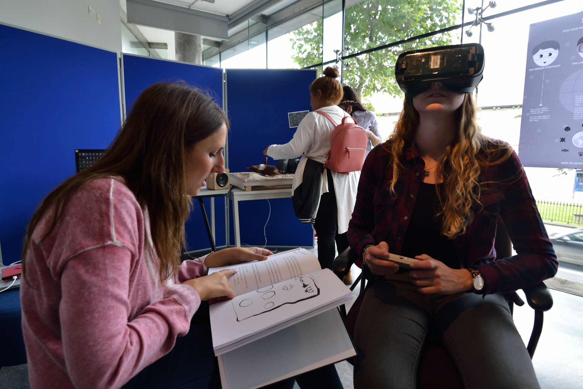 Visitors playing KORE - One player reading instruction for the player 1 and player 3 is controlling the analog controls 