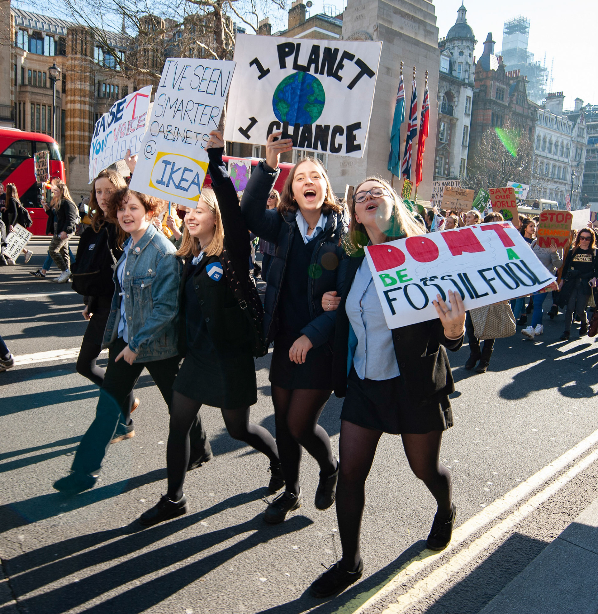Group of schoolgirls hold up placards whilst marching